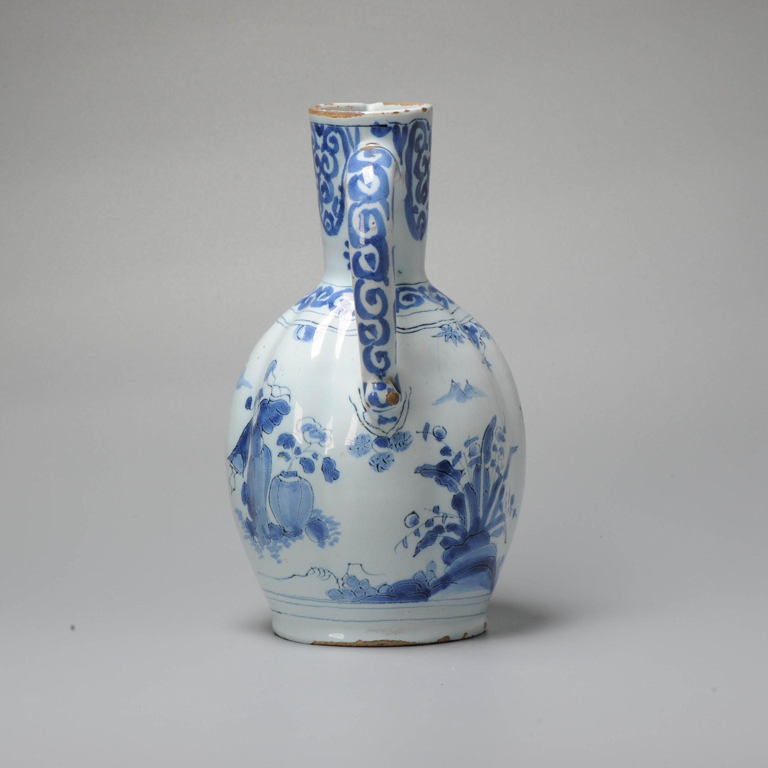 Earthenware ewer of ovoid ribbed body on spreading foot, cylindrical neck and a large mouth with a pinched spout. Curved handle. The shallow conical base is glazed and has a piece of lead attached. Decorated in different shades of blue on a white