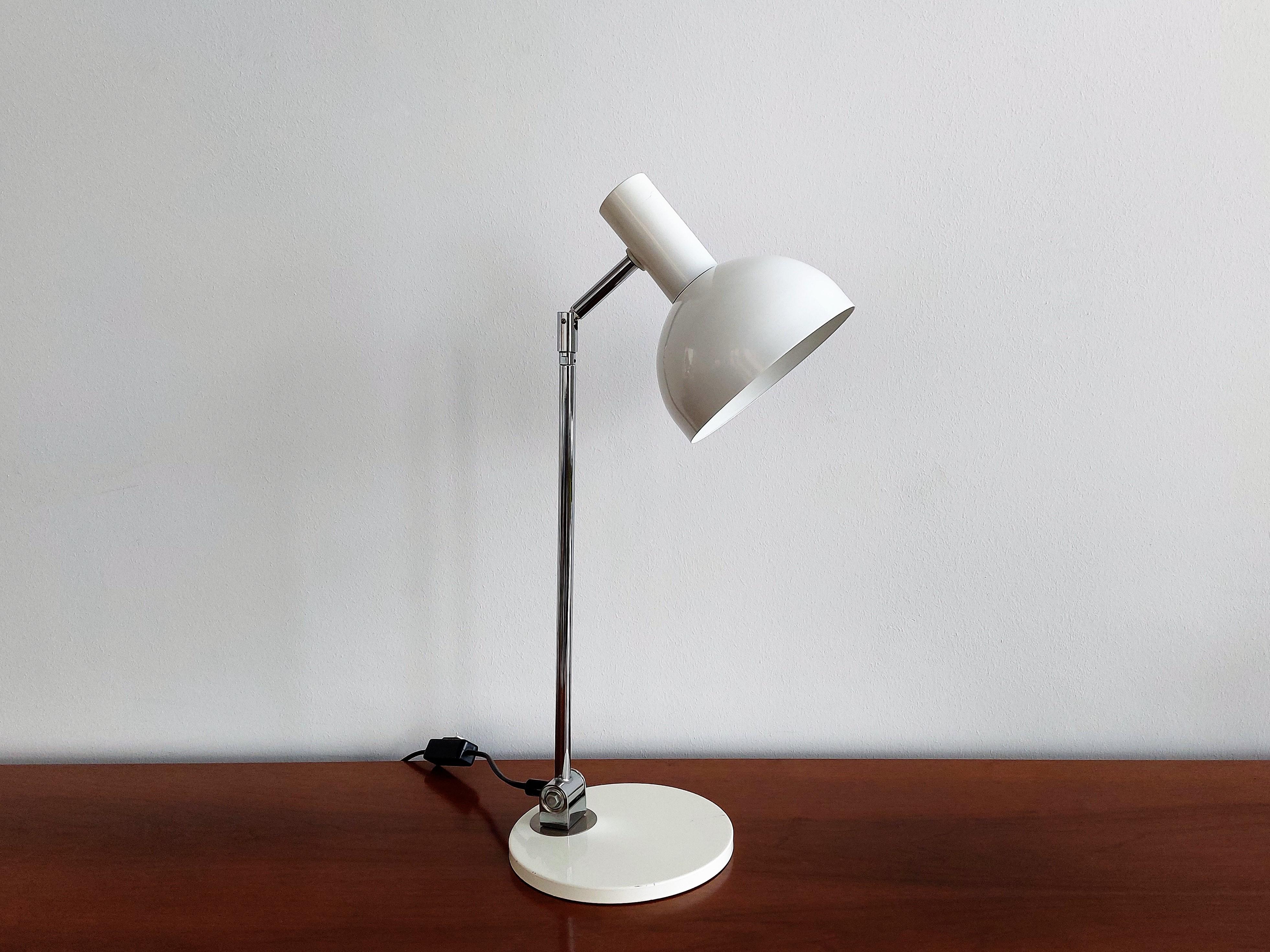 This table lamp is very much in the style of the 'ball in socket' floor lamp by H. Busquet for Hala Zeist and also a desk lamp from Raak. It has a round white base and shade with a chromed metal adjustable arm in between. The lamp is perfect as a
