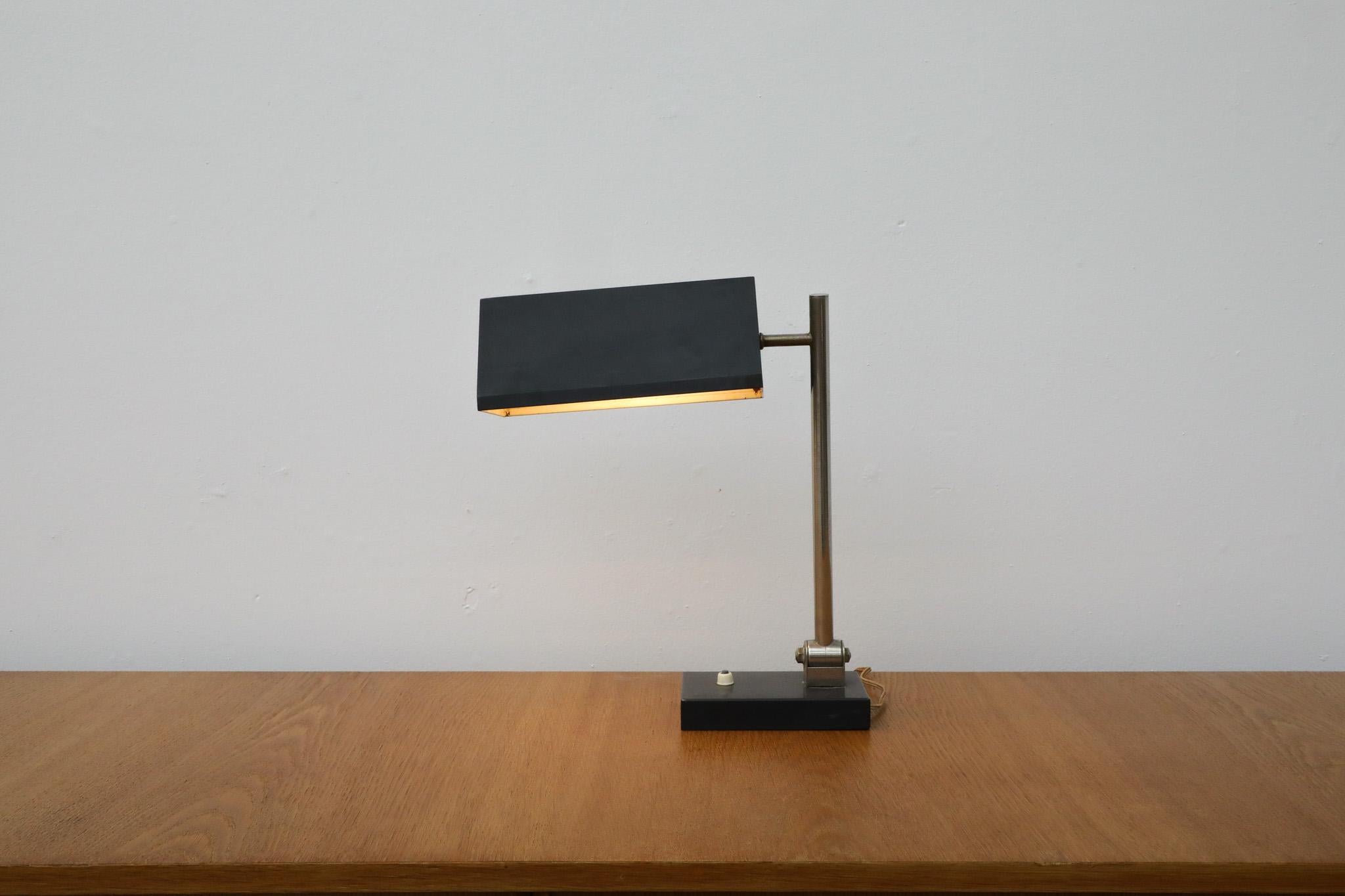 Vintage Mid-Century desk lamp by Dutch post-war design great H. Busquet for the renowned Hala Zeist lighting manufacturing company. Made in the mid 1950s. The light sports a black enameled triangular metal shade seated atop an articulating chrome