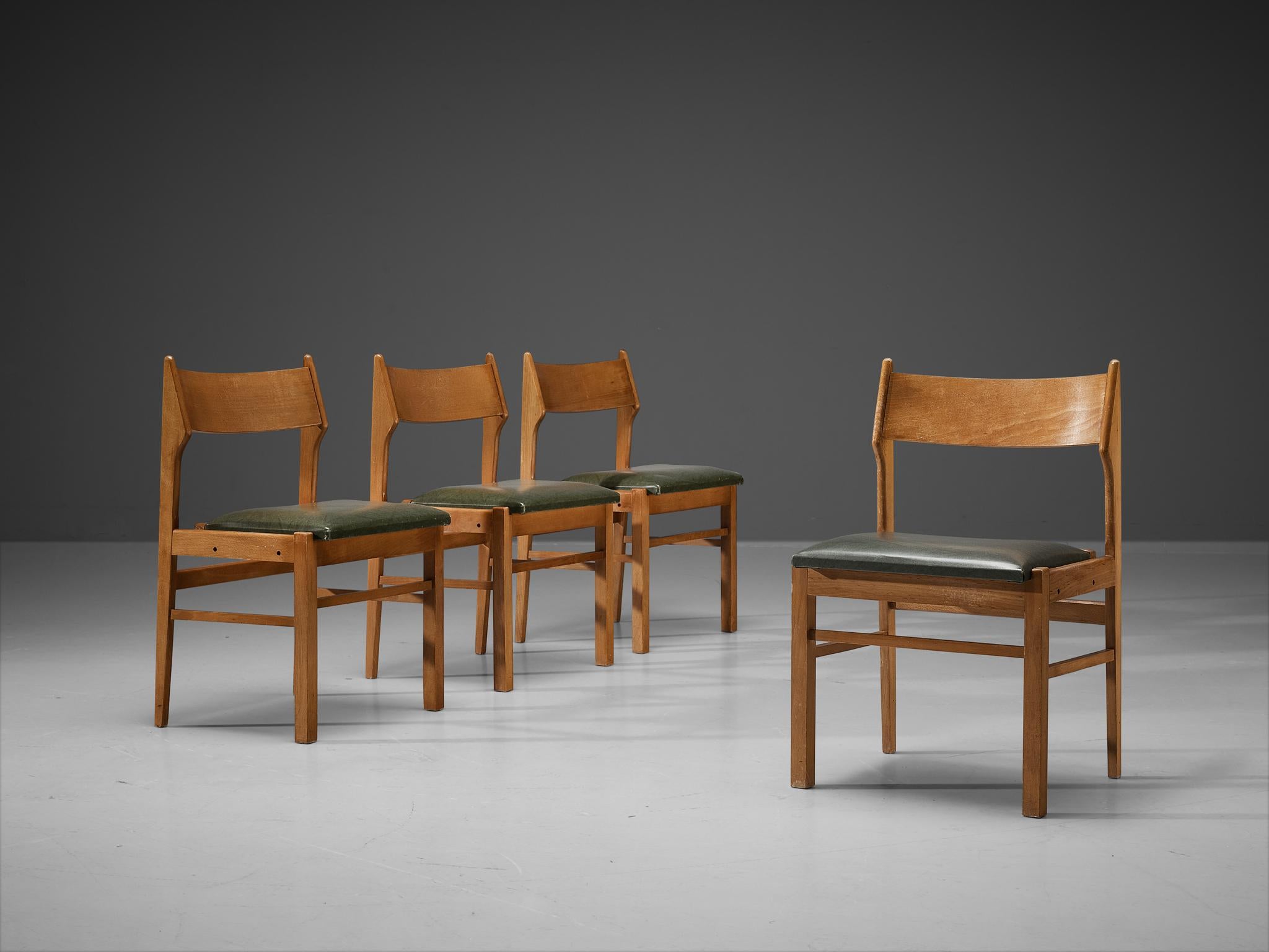 Dining chairs, wood, dark green leatherette, The Netherlands, 1960s. 

Modest set of four Dutch dining chairs. Its design shows clear lines and an airy backrest. The dark green leatherette seats give a striking contrast with the warm color of the