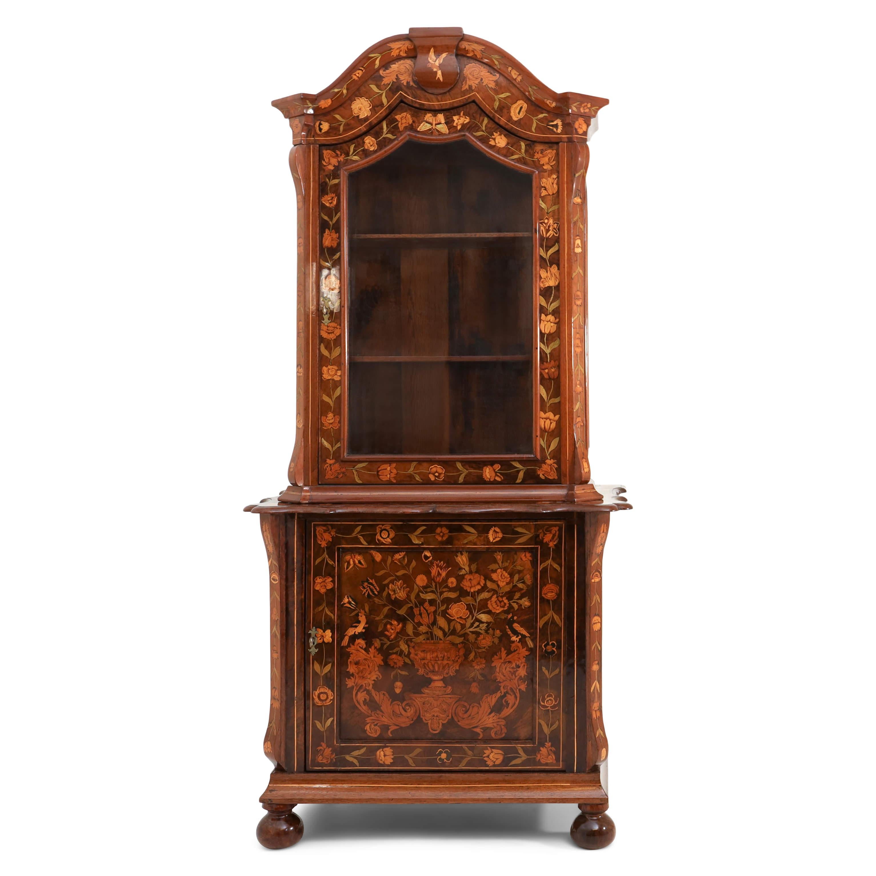 Dutch Baroque style display cabinet with floral marquetry all-over. The single-door base cabinet with wavy top is decorated with a large inlay in the form of a floral bouquet on the door. The top is glazed on three sides and closes with an arch. The