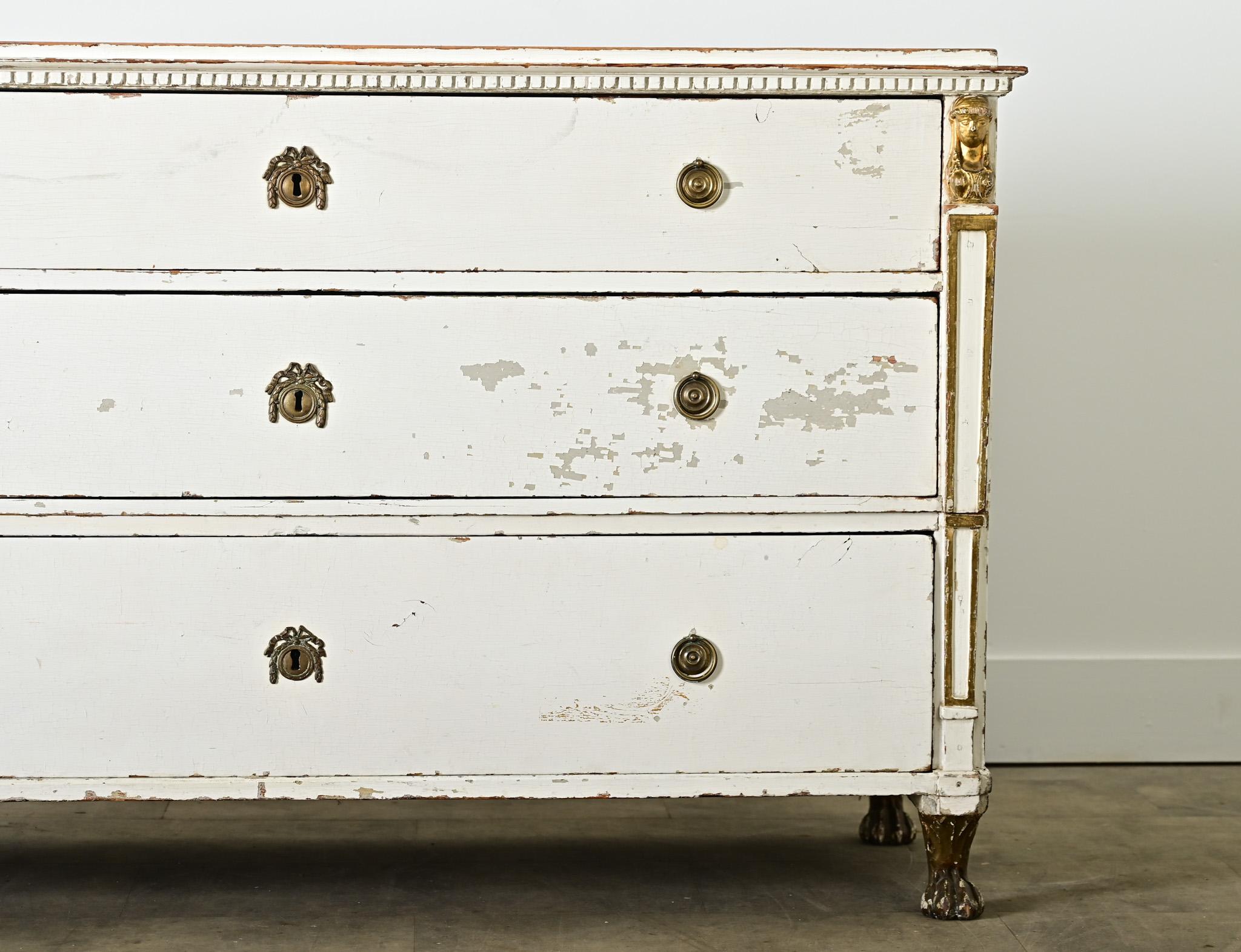 Commode à trois tiroirs de style Empire hollandais datant du XIXe siècle, avec sa finition peinte d'origine et des touches d'influence napoléonienne sur la construction en pin. La surface supérieure a perdu une grande partie de sa peinture blanche