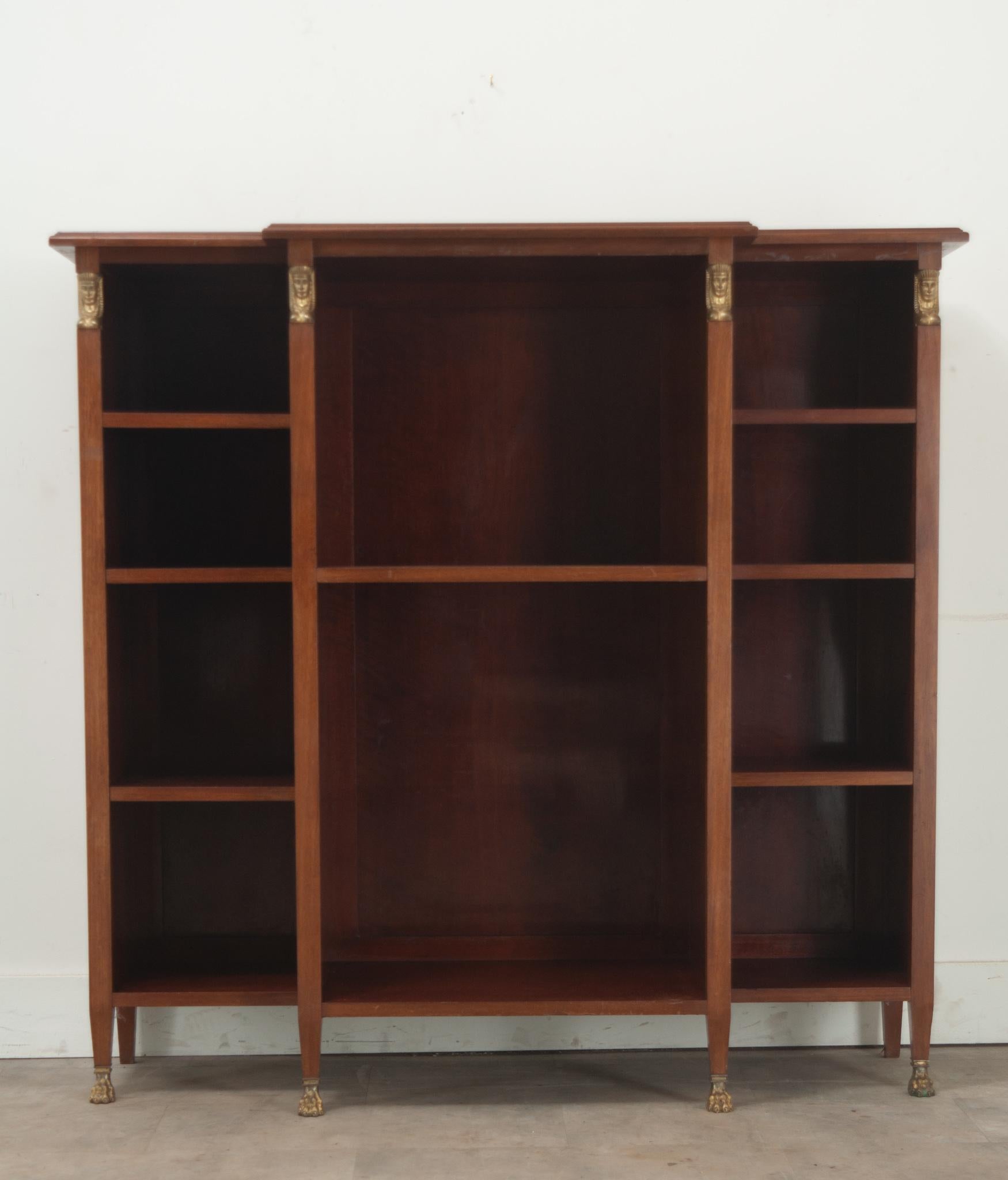 A practical Empire style bookshelf made of mahogany, perfect for storing your books and display objects. The center and deepest cavity has a single 16” deep adjustable shelf flanked by two more narrow cavities with three 12”deep adjustable shelves.