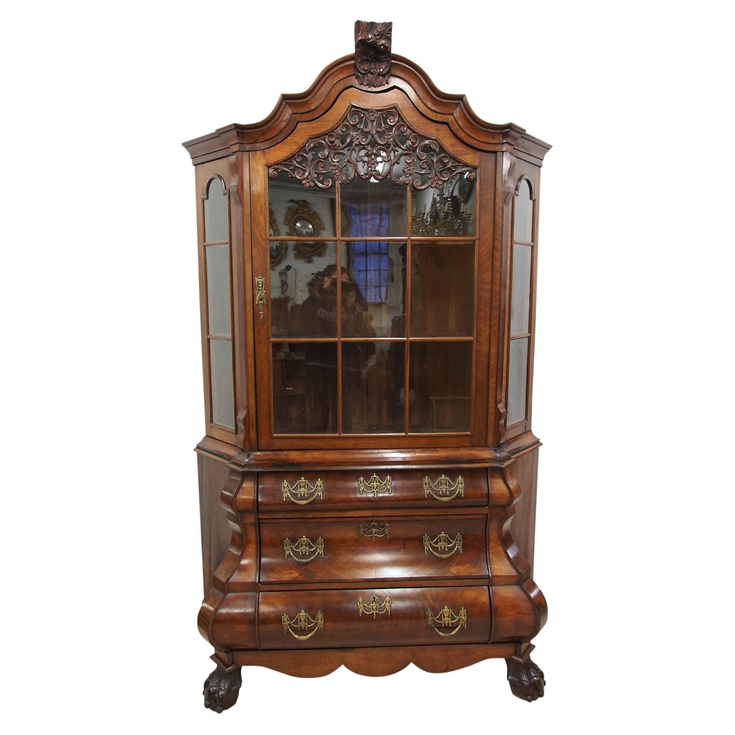 Dutch figured walnut bombe-front bookcase, circa 1860. With a square astragal glazed door in the further astragal glazed windows to the sides. The door has a foliate pierced carved decoration and a shaped arched cornice above with further foliate