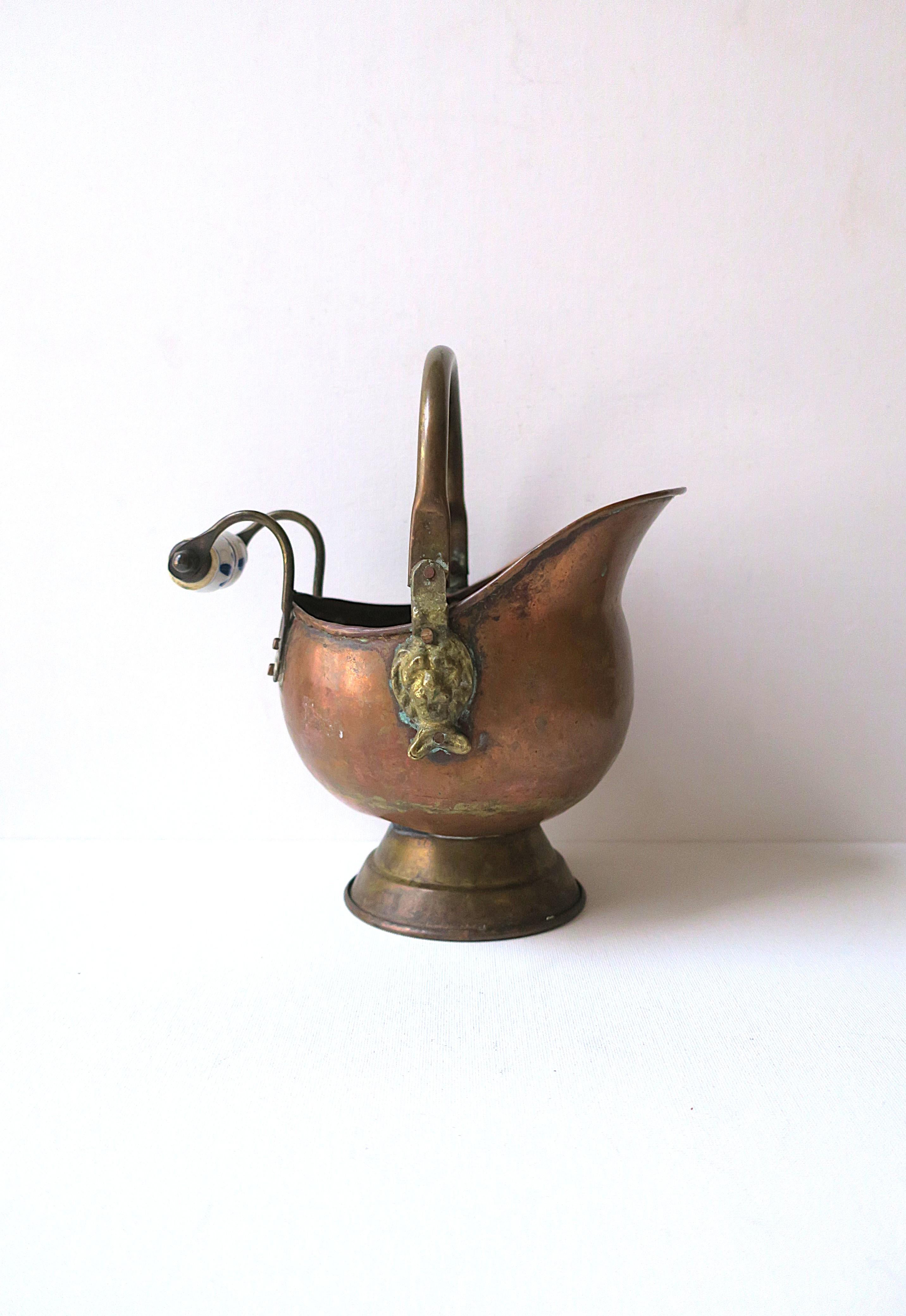 A small Dutch copper and brass fireplace scuttle bucket with lion head design and blue and white Delft dandle, circa early, 20th century, Holland. Handle is adjustable up/down/side to side, as shown in images. Dimensions: 7.5