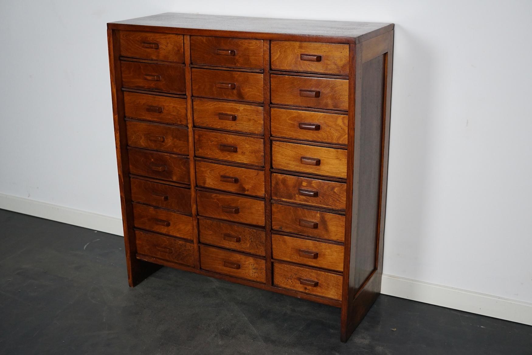This apothecary cabinet was made circa 1950s in the Netherlands. The cabinet was used on a school to store painting supplies. It features 24 drawers with wooden handles. The interior dimensions of the drawers are: D W H 28 x 22 x 7.5 cm. It shows