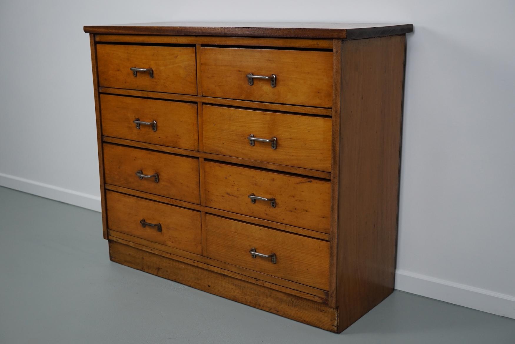 This apothecary cabinet was made circa 1950s in the Netherlands. The cabinet was used on a school to store painting supplies. It features 8 large drawers with metal industrial handles. The interior dimensions of the drawers are: D W H 32 x 45 x 14