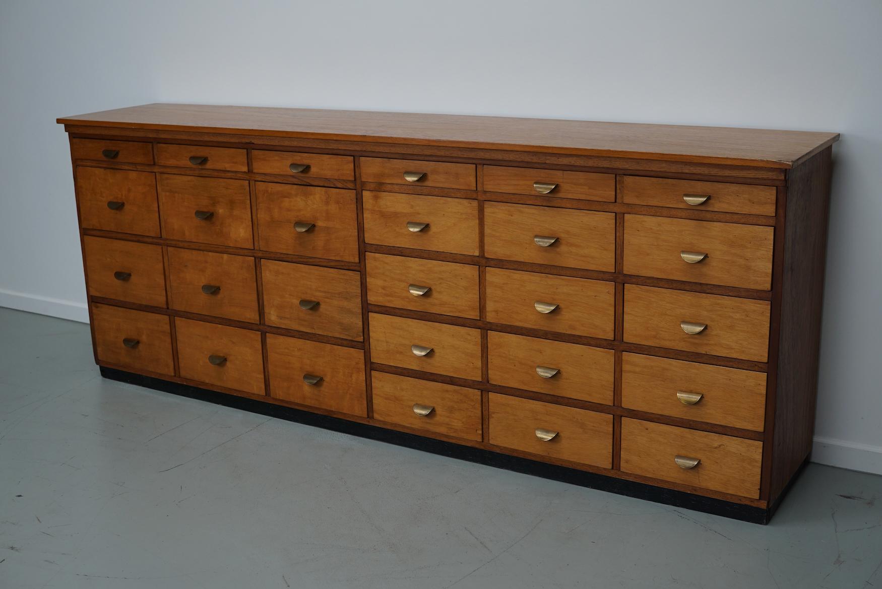This apothecary cabinet was made circa 1950/60s in the Netherlands. The cabinet was used on a school to store painting supplies. It features 27 drawers in 3 different sizes with brass handles. The interior dimensions of the drawers are: D W H 31 x