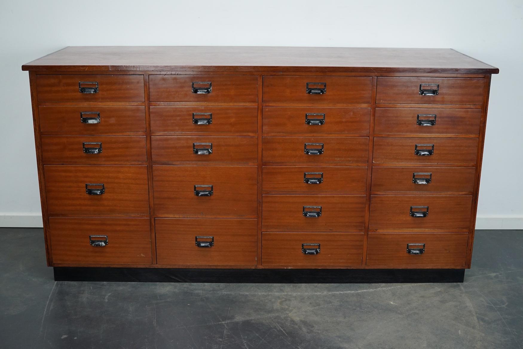This apothecary cabinet was made circa 1950s in the Netherlands. The cabinet was used in a fabrics shop as a counter. It features 22 drawers with black metal handles. The interior dimensions of the drawers are: D W H 53 x 38 x 8 / 12 / 18 cm.