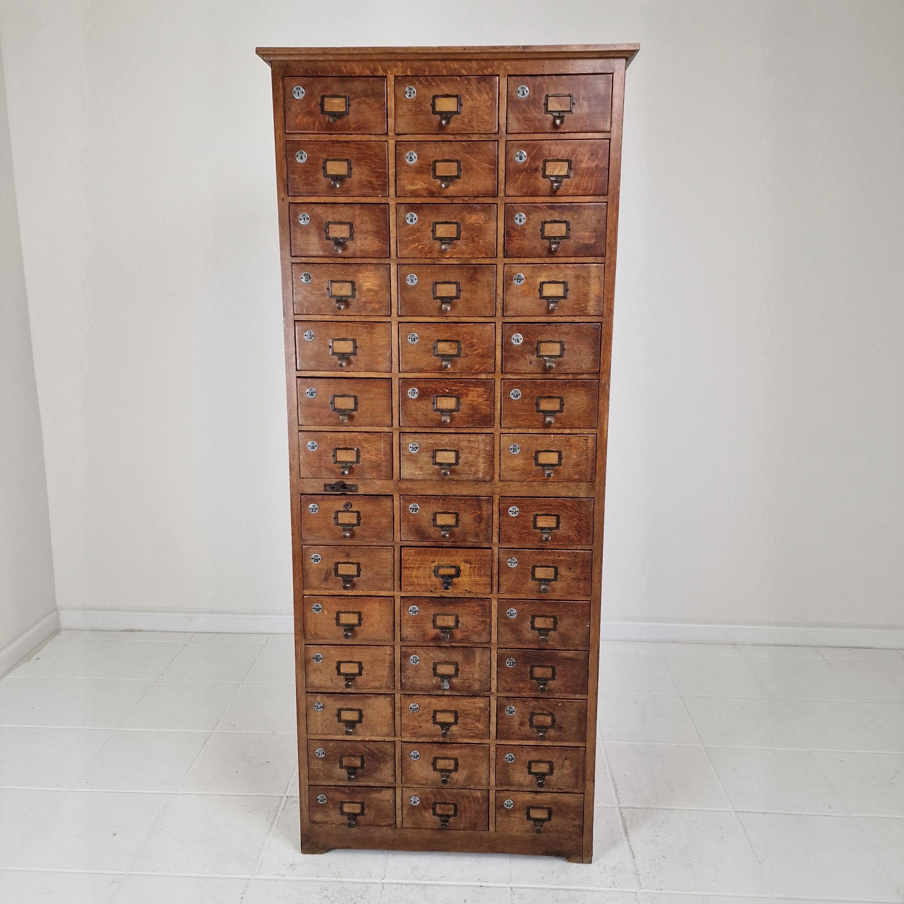 Un llamativo mueble industrial holandés de principios del siglo XX con 42 cajones numerados, fabricado en roble macizo y que destila artesanía atemporal. 
Utilizada originalmente en un archivo, botica o taller, esta pieza alta y estrecha combina un