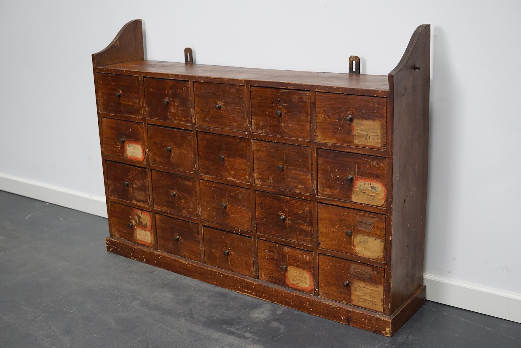 Cette armoire d'atelier a été fabriquée en pin aux Pays-Bas dans les années 1920 et était utilisée dans un atelier de réparation de vélos jusqu'à récemment. Il comporte 20 tiroirs avec de petits boutons. Certains des tiroirs ont des séparateurs. Les