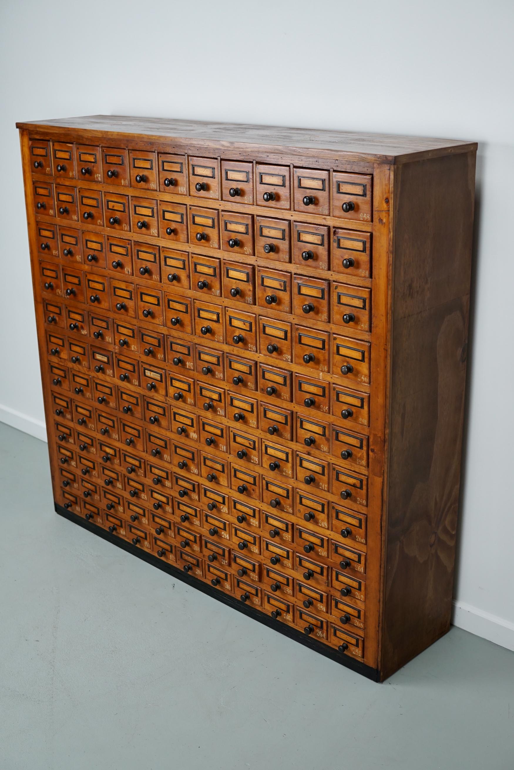 This workshop cabinet was made from pine in the Netherlands circa 1930s and it was used in a workshop for dentist equipment. It features many drawers with small knobs and name card holders. The interior dimensions of the drawers are: DWH 25 x 8 x 8