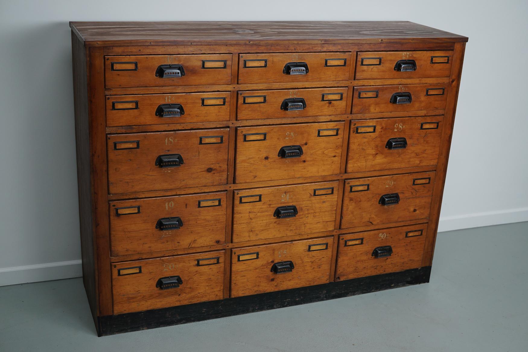 This workshop cabinet was made from pine in the Netherlands circa 1930s and it was used in a workshop for dentist equipment. It features many drawers with small knobs and name card holders. The interior dimensions of the drawers are: DWH 35 x 37 x