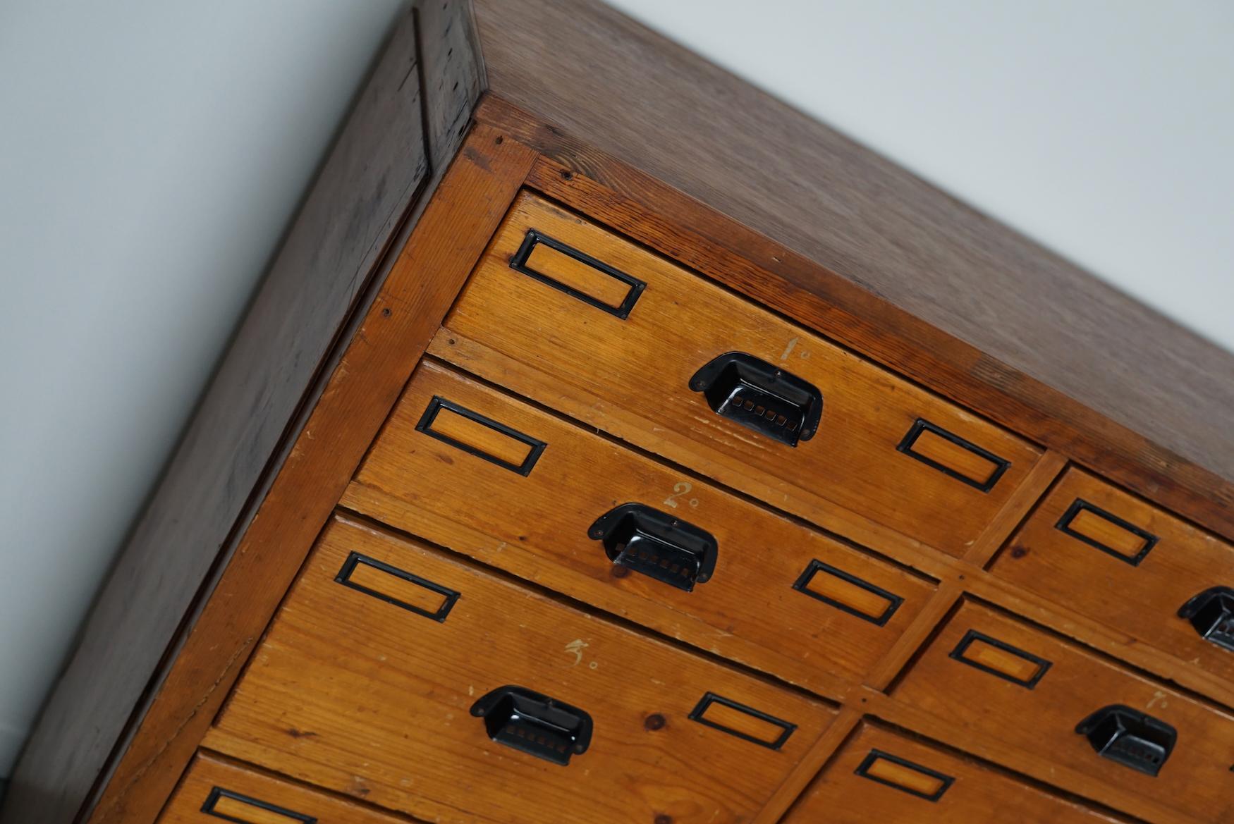 This workshop cabinet was made from pine in the Netherlands circa 1930s and it was used in a workshop for dentist equipment. It features many drawers with nice handles and name card holders. The interior dimensions of the drawers are: DWH 35 x 37 x