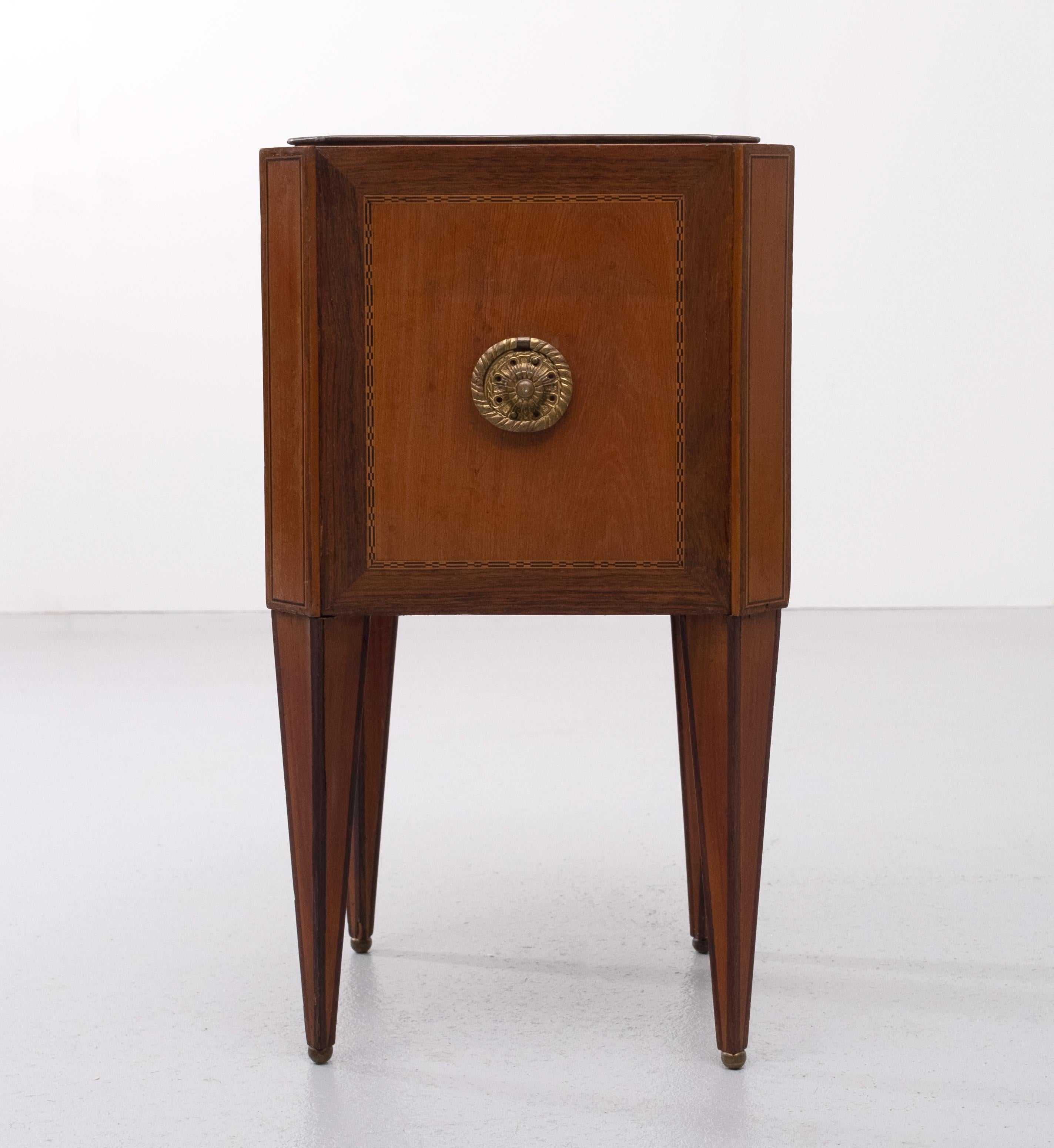 Circa 1850, neat-sized Dutch inlaid mahogany jardinière. The square top with canted corners, containing its original brass liner. The sides with chevron inlay, banding, shell inlays, and circular Brass ring handles. Supported on square, tapering,