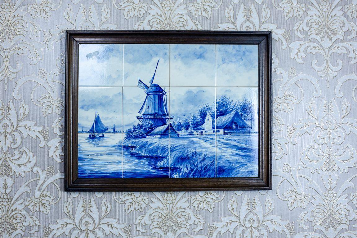 We present you a picture made of ceramic tiles that depicts Dutch landscape. 
The whole is closed in an oak frame and comes from the 1960s. 
Furthermore, the landscape is underglaze, in cobalt which is commonly known as “delft blue” – the name