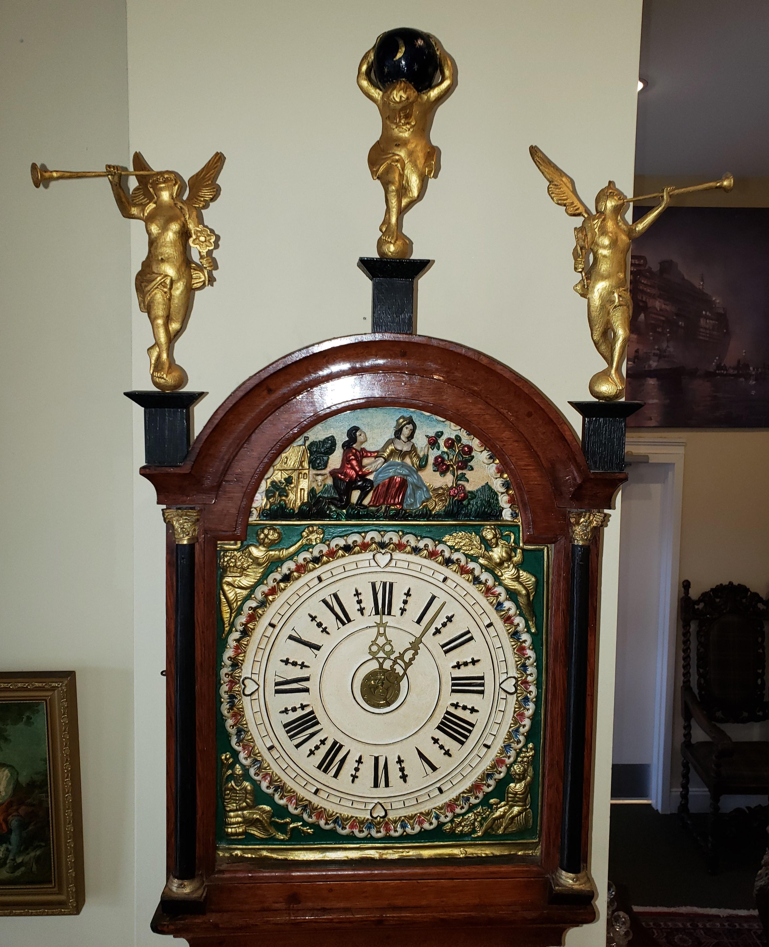 Dutch mahogany Friesian 30 hour wall clock. Gold gilt angels sit atop with man holding Atlas in the center. Hand painted face. A brass urn covers the pendulum. This clock should be wound once a day.