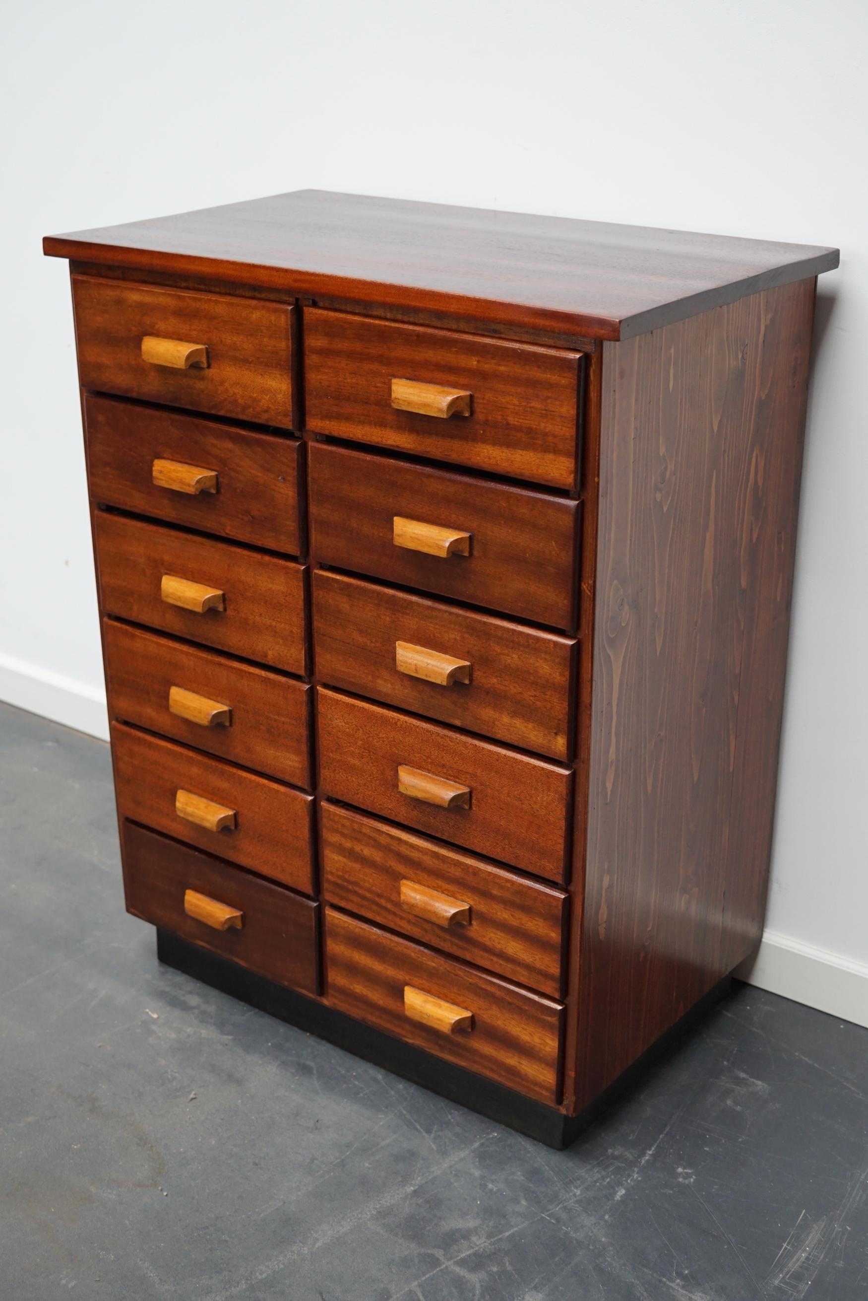 This cabinet was designed and made in circa 1930s in the Netherlands. It features 12 drawers and is made of pine and mahogany with wooden handles. The cabinet is in a good vintage condition. The inside drawer measurements are DWH: 33 x 25 x 8.5 cm.