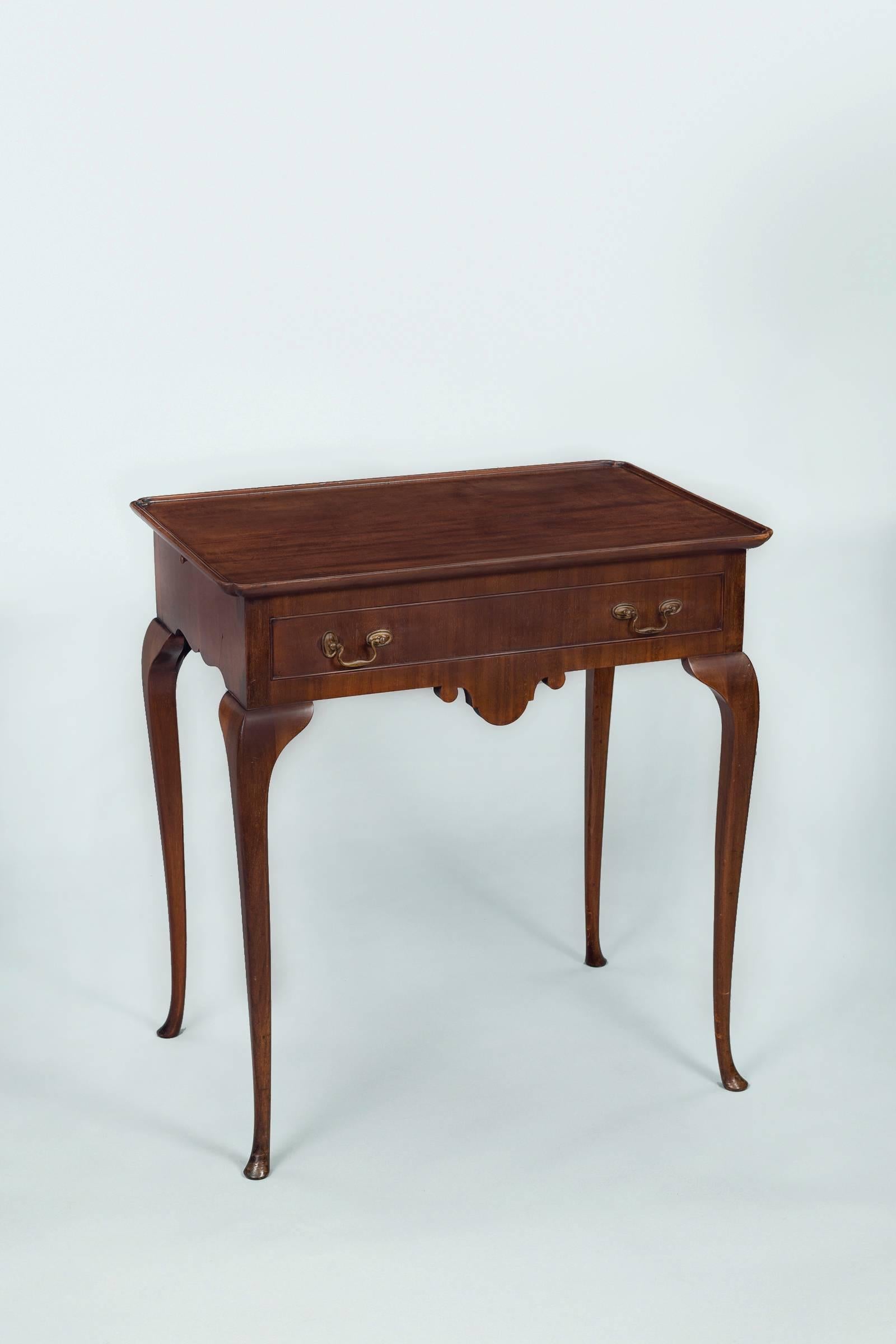 Elegant Dutch mahogany tea table with molded tray-top, notched corners, shaped frieze on all four sides, pull-out candle slides, brass swan neck handle hardware, raised on cabriole legs.