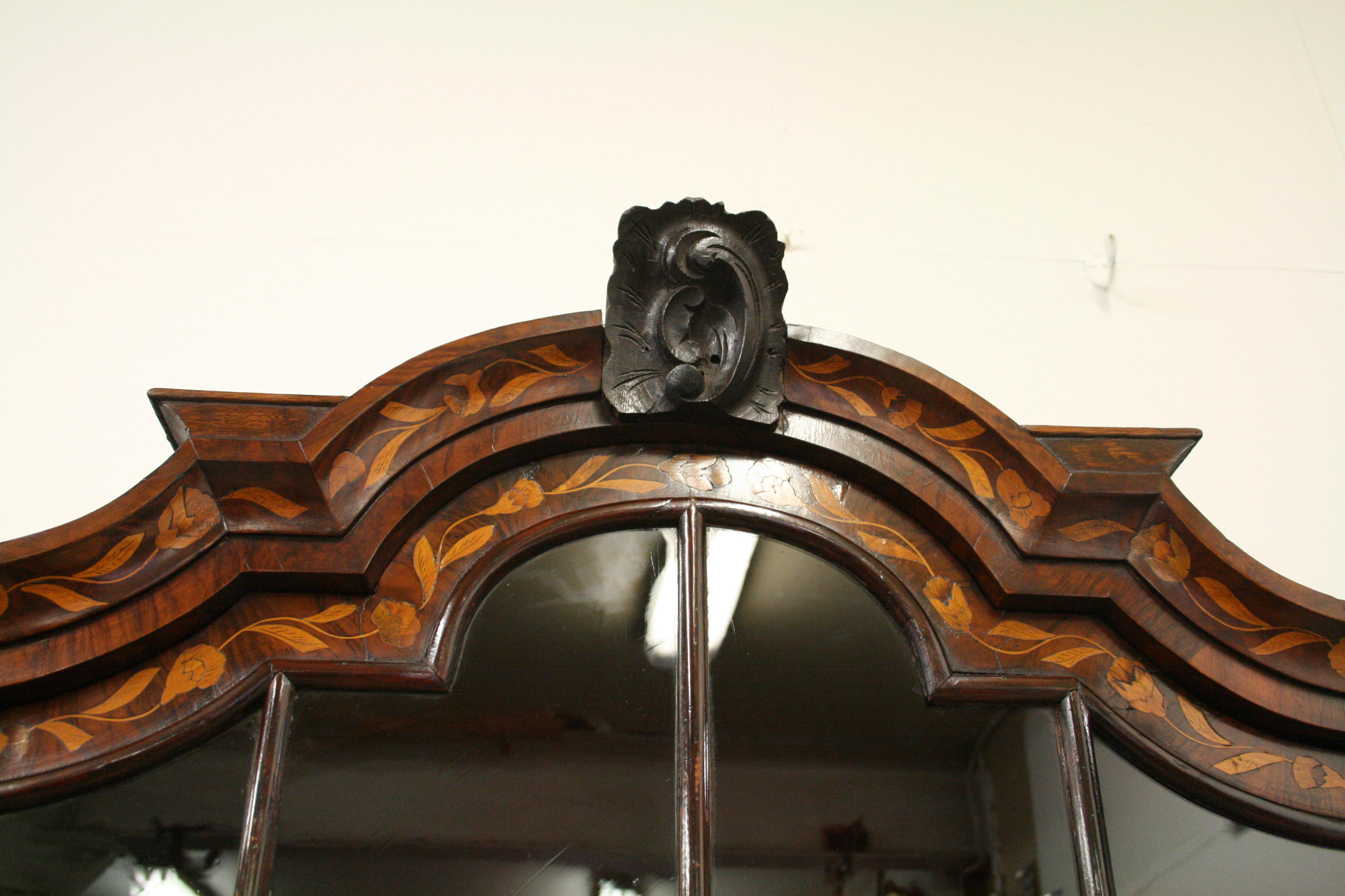 Dutch marquetry 2 part display cabinet. The top with its typical Dutch stepped sections has flat pieces on the cornice for putting vases and a carved section in the centre. Below this is an arched and astragal glazed door. Inside is lined with felt