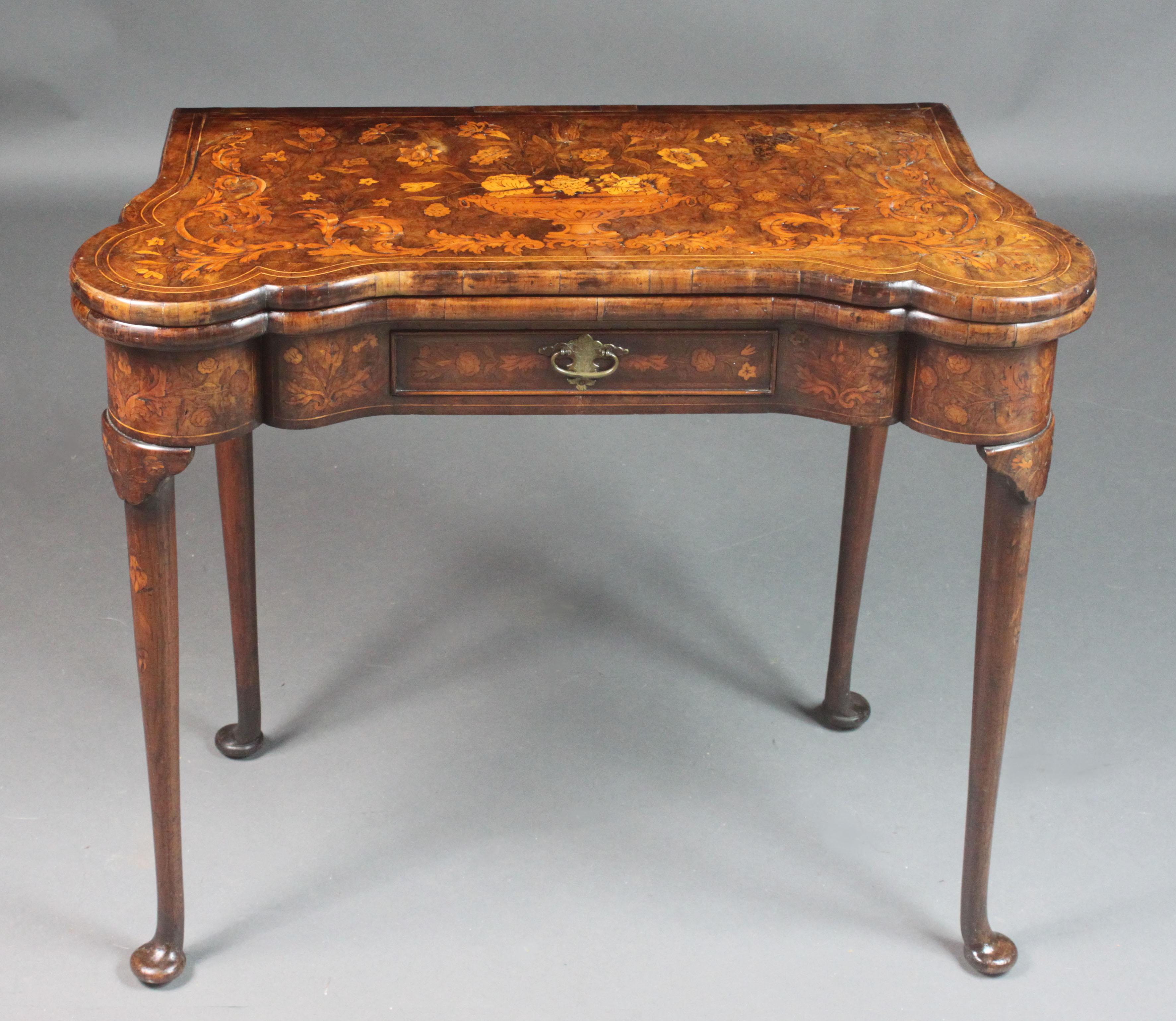 A good Dutch walnut pad foot card table with attractive marquetry inlay of birds and flowers; both back legs hinge on a knuckle joint to support the table when open, the interior with counter wells and inlaid with the four card suits. Oak-lined