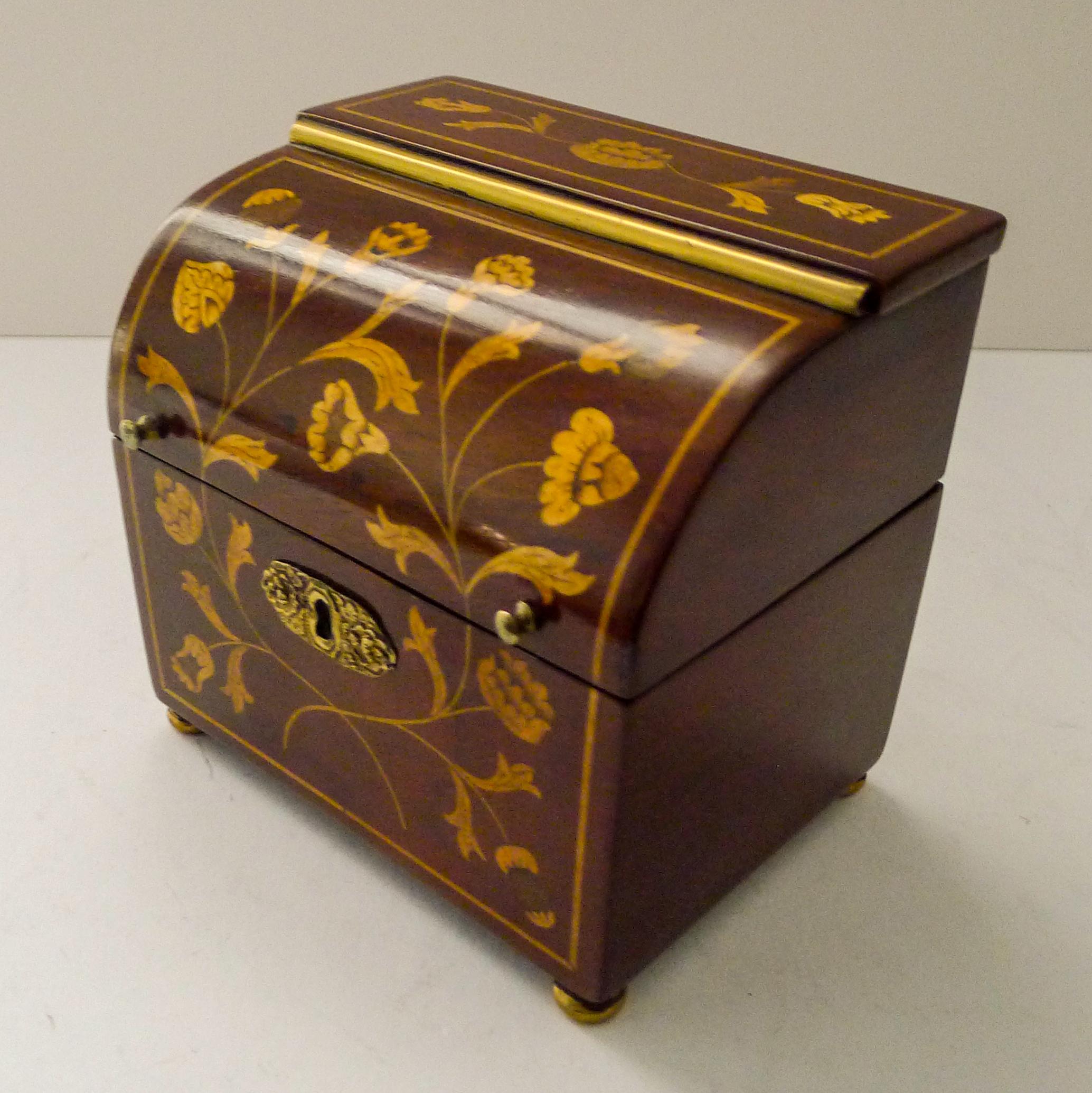 This wonderful early nineteenth century tea caddy was made to emulate the larger decanter boxes made in a similar shape and manor during this period.

Made from Mahogany, the box is beautifully decorated with stunning floral and foliate marquetry