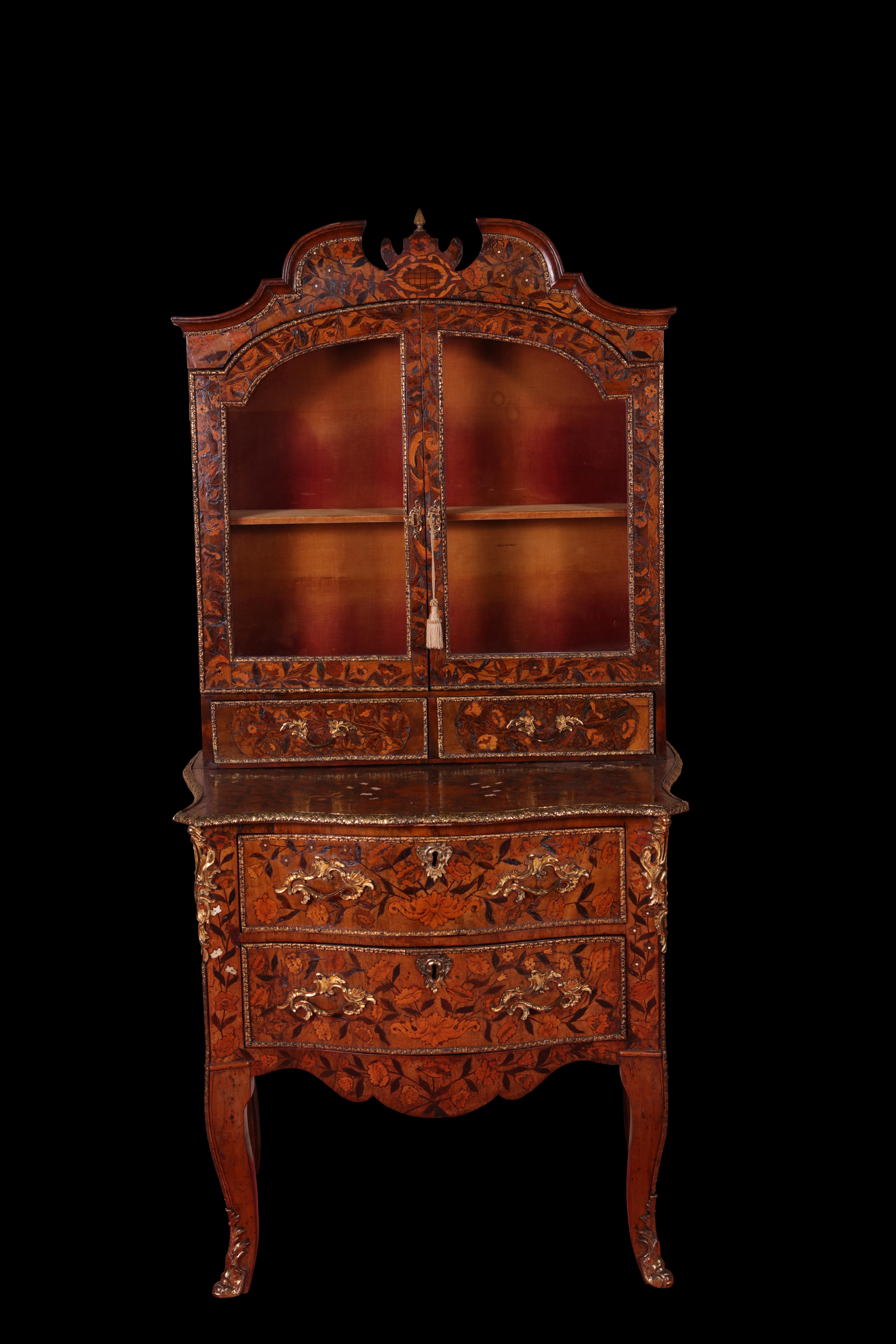 Eine flämische Intarsienvitrine auf einer Kommode aus dem 18. Jahrhundert, mit einem geformten Scheitel, in dessen Mitte sich ein Endstück befindet, über zwei verglasten Türen, die sich zu einem Schrank mit Regalen öffnen. Die Vitrine steht auf