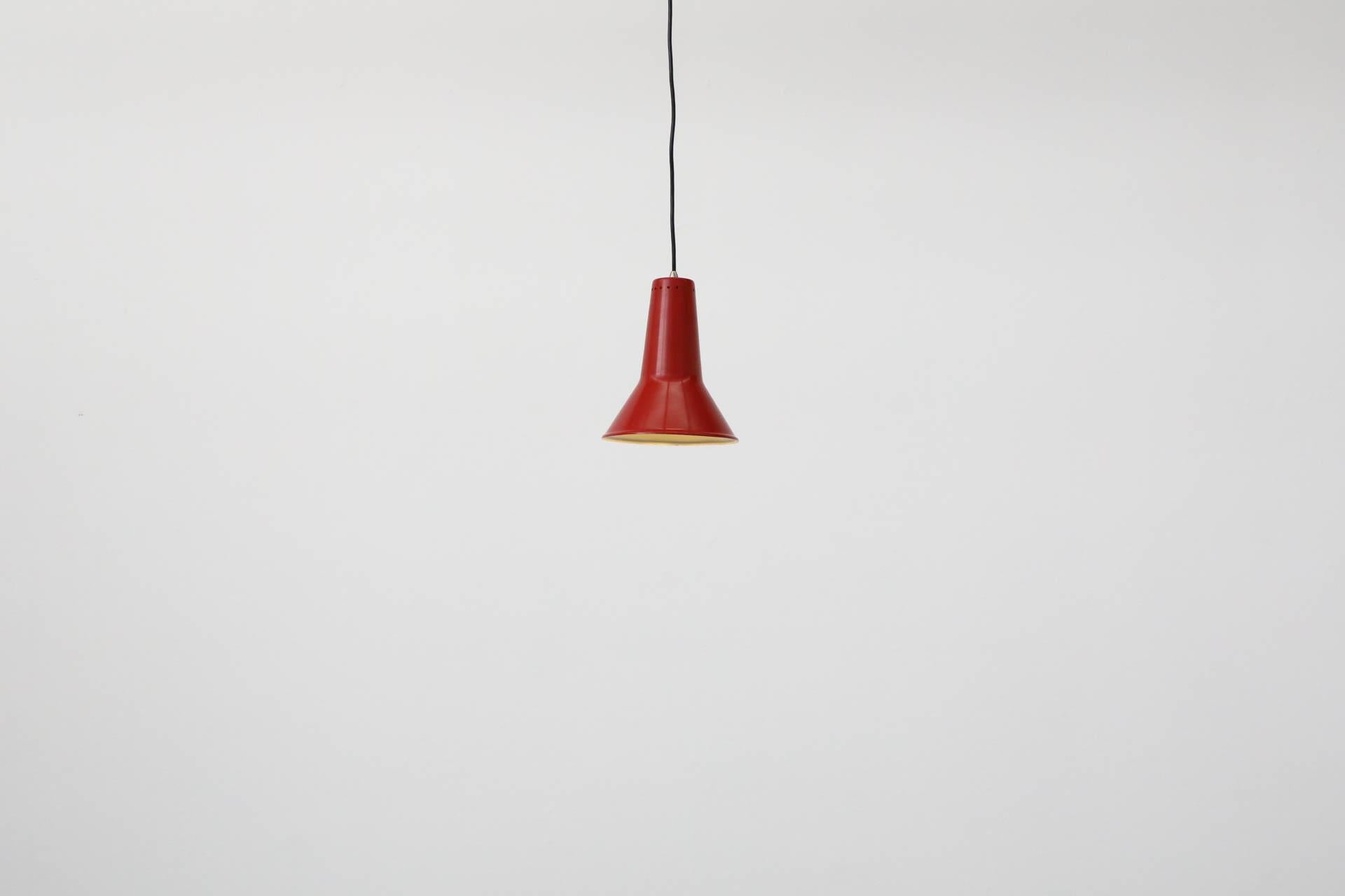 Lampada a sospensione singola di metà secolo olandese con paralume a cono in alluminio smaltato rosso con piccoli tagli a pois nella parte superiore. Progettato negli anni '50 da Willem Hagoort. La sua azienda 