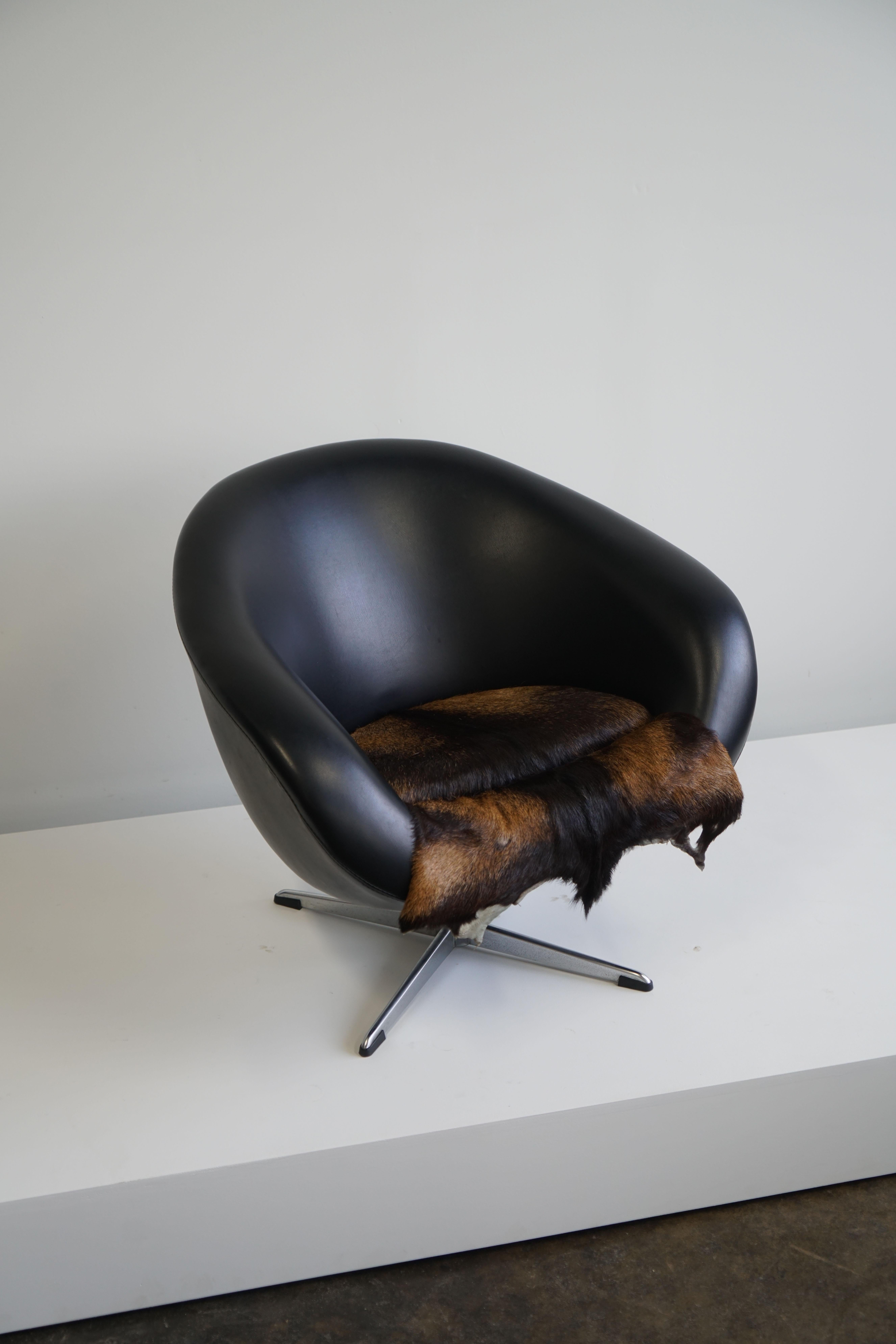 A dutch mid-century swivel tub chair in black leather with fur pad.
Chair is a smaller sized chair, measuring 26