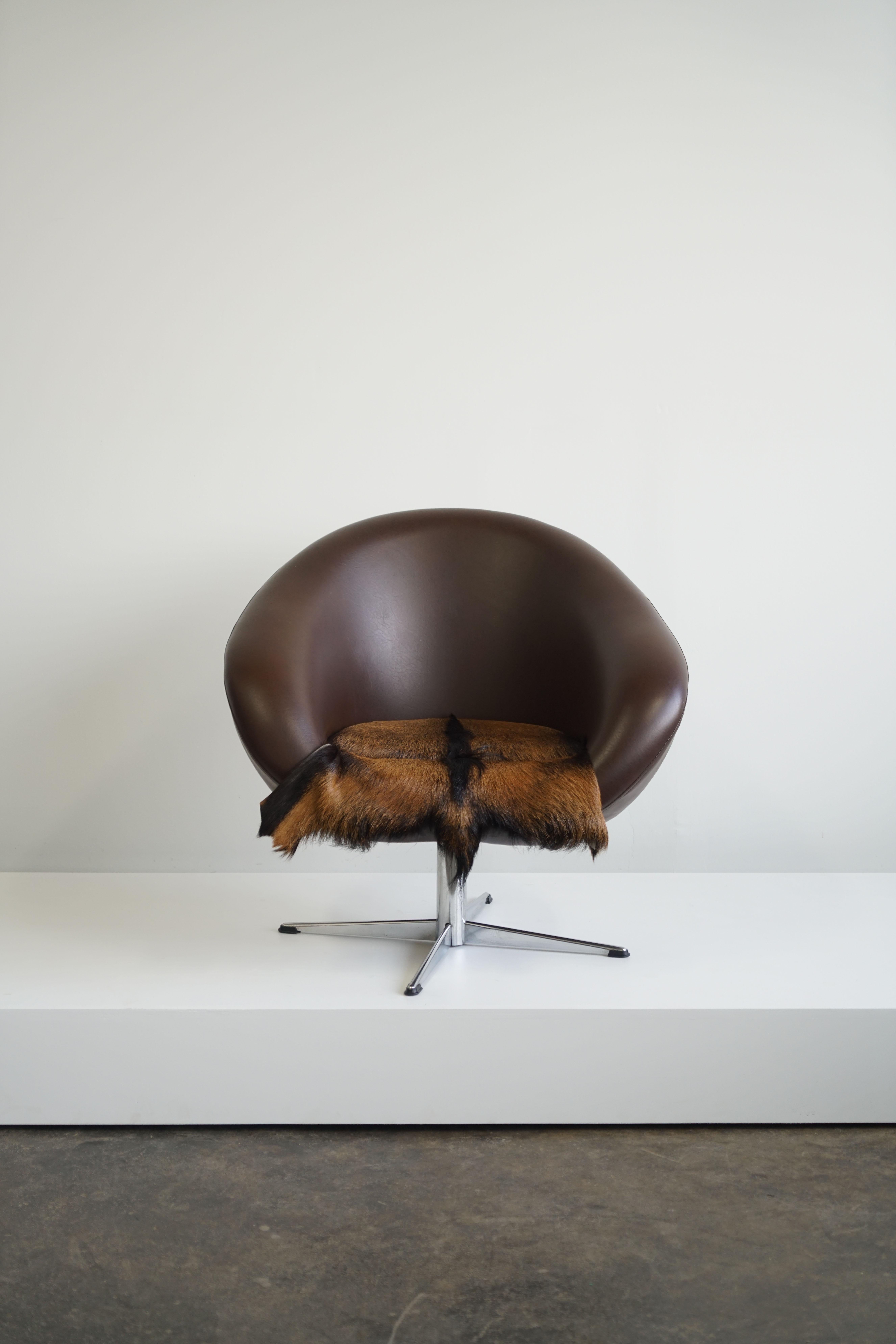 A dutch mid-century swivel tub chair in brown leather with fur pad.

Fur pad is fixed to seat. 

Slightly smaller black chair also available. 

Condition: Overall very good vintage condition. Some slight, shallow scratches on the backside as