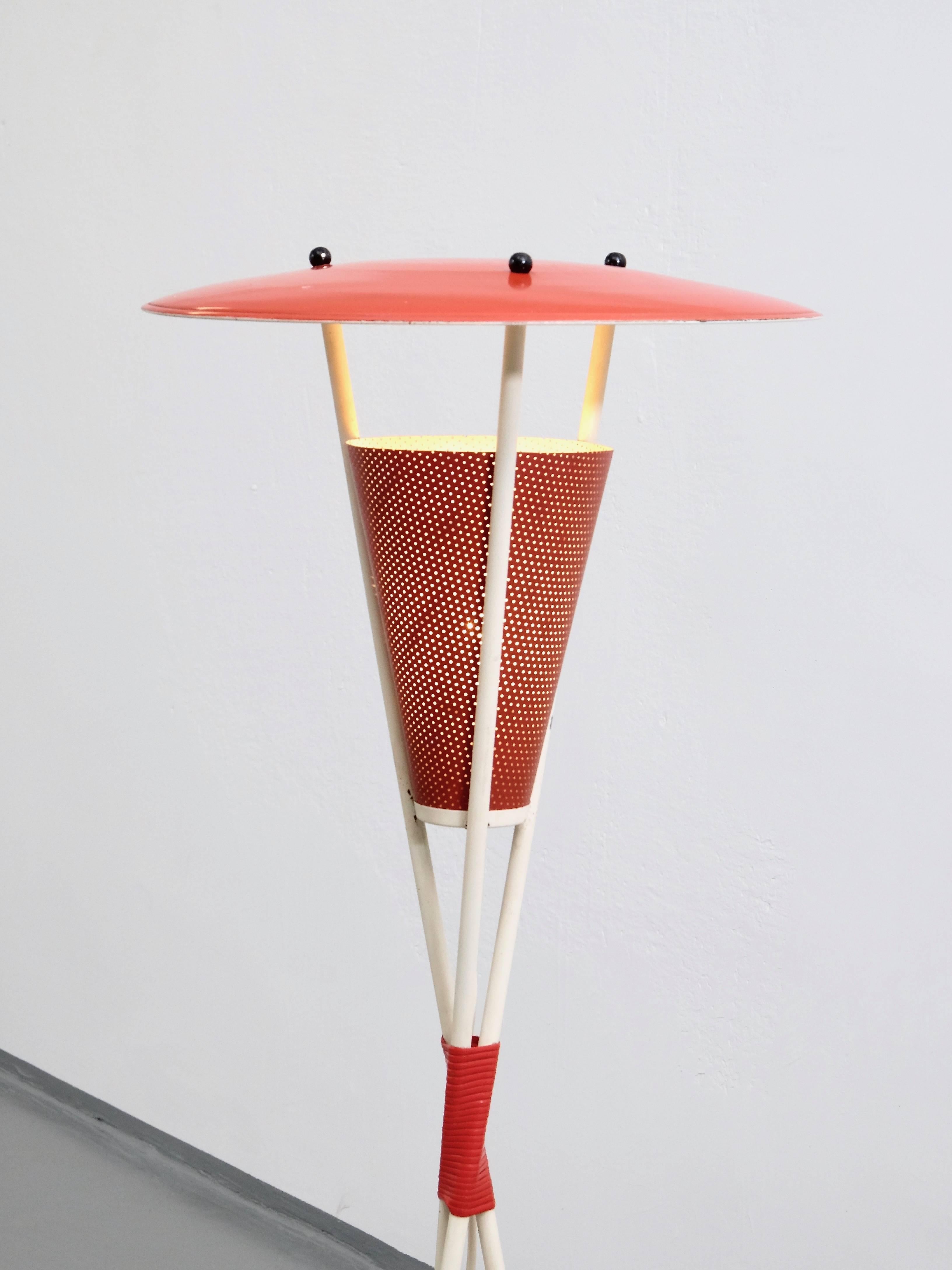 Midcentury tripod floor lamp from Holland. This lamp has a white tripod base, black spherical ball screws and it is wrapped in the middle with red plastic. The shade and the diffuser is lacquered red. It is in a good original condition, small marks