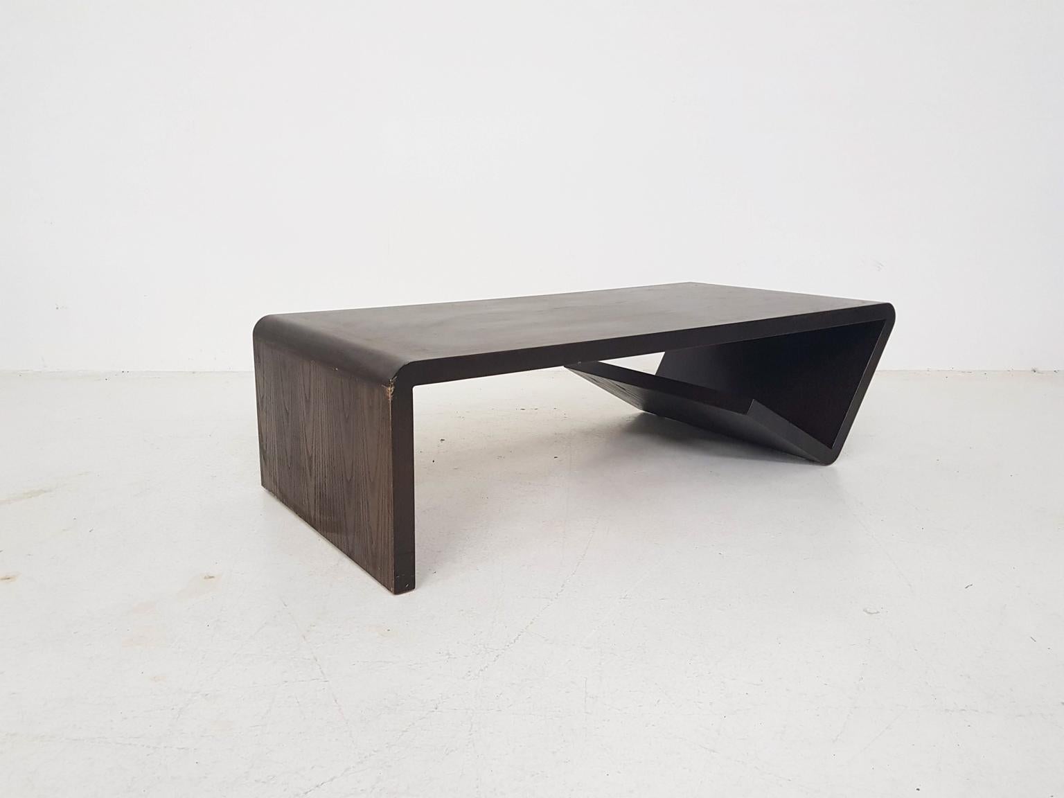 Heavy oak coffee table with a dark brown color, made and designed in the Netherlands in the 1970s. The table is made of one piece, which has a stylish curved shaped. The shape end underneath the table and forms a storing place for magazines.
We