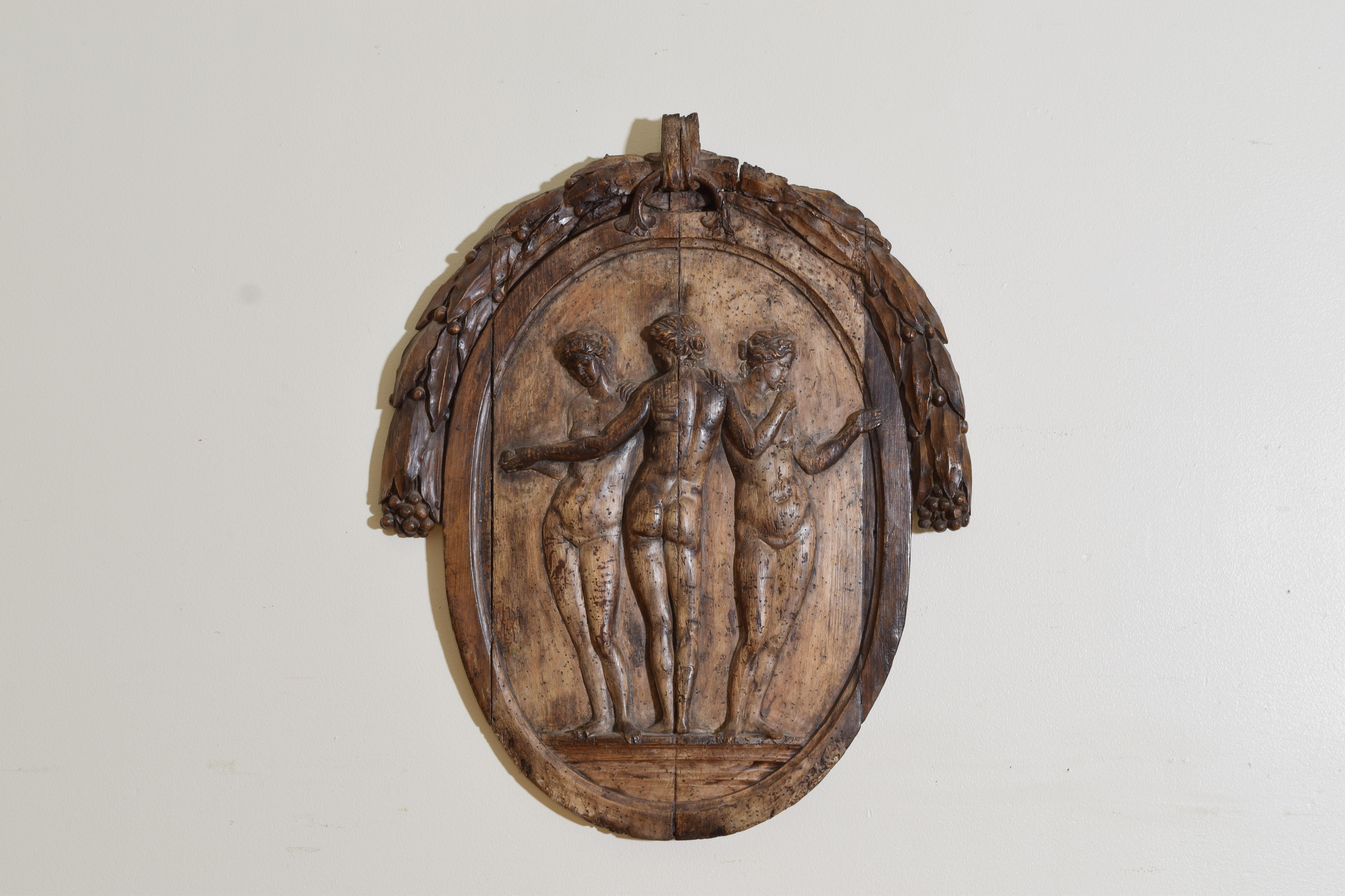 Relief carving of pinewood depicting The Three Graces, one of the most classical subjects of Greek and Roman antiquity.  Carving tools are used to create the image until it becomes three dimensional and protrudes from the background.  Wheat is