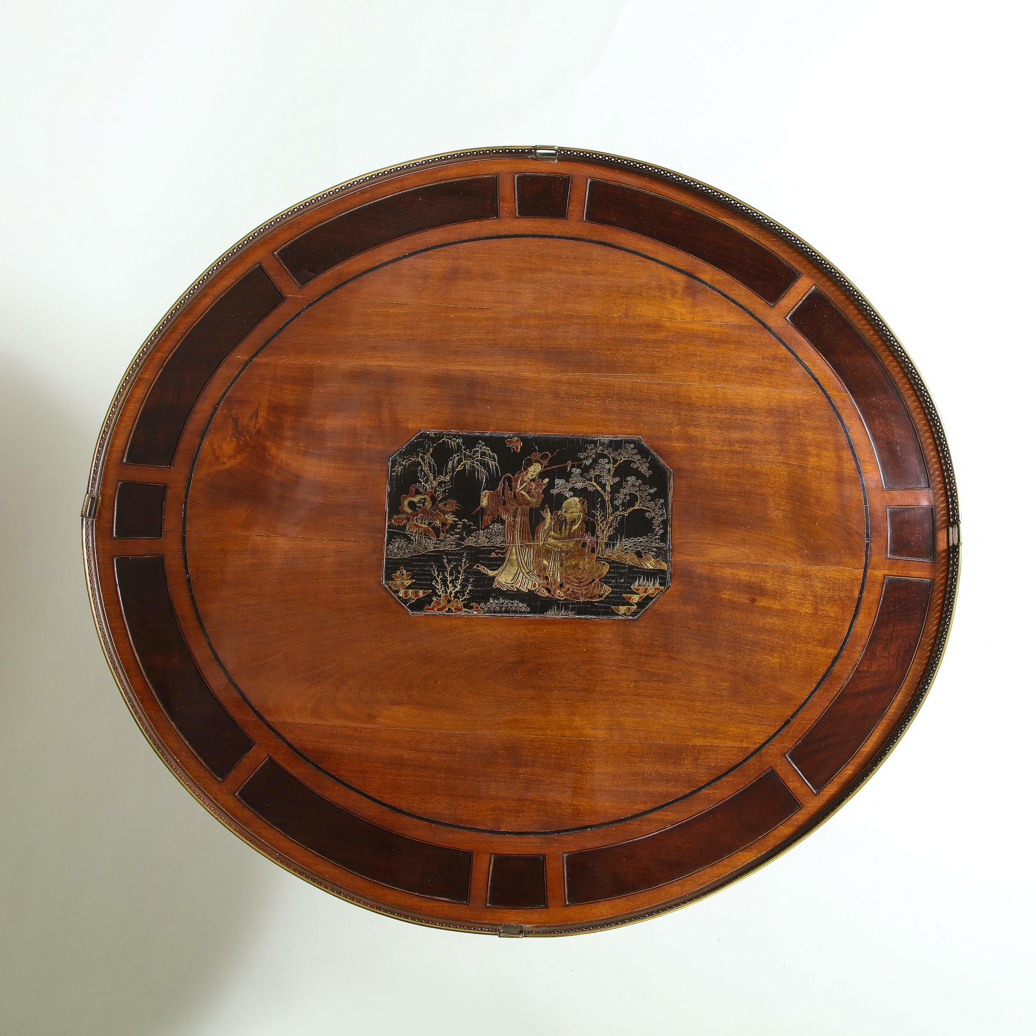 The slightly oval satinwood top inlaid with a Chinese lacquer panel and purpleheart-inset border, further mounted with a gilt-brass gallery; raised on four black-lacquer inlaid sabre legs joined by a central stretcher; on ball-form
