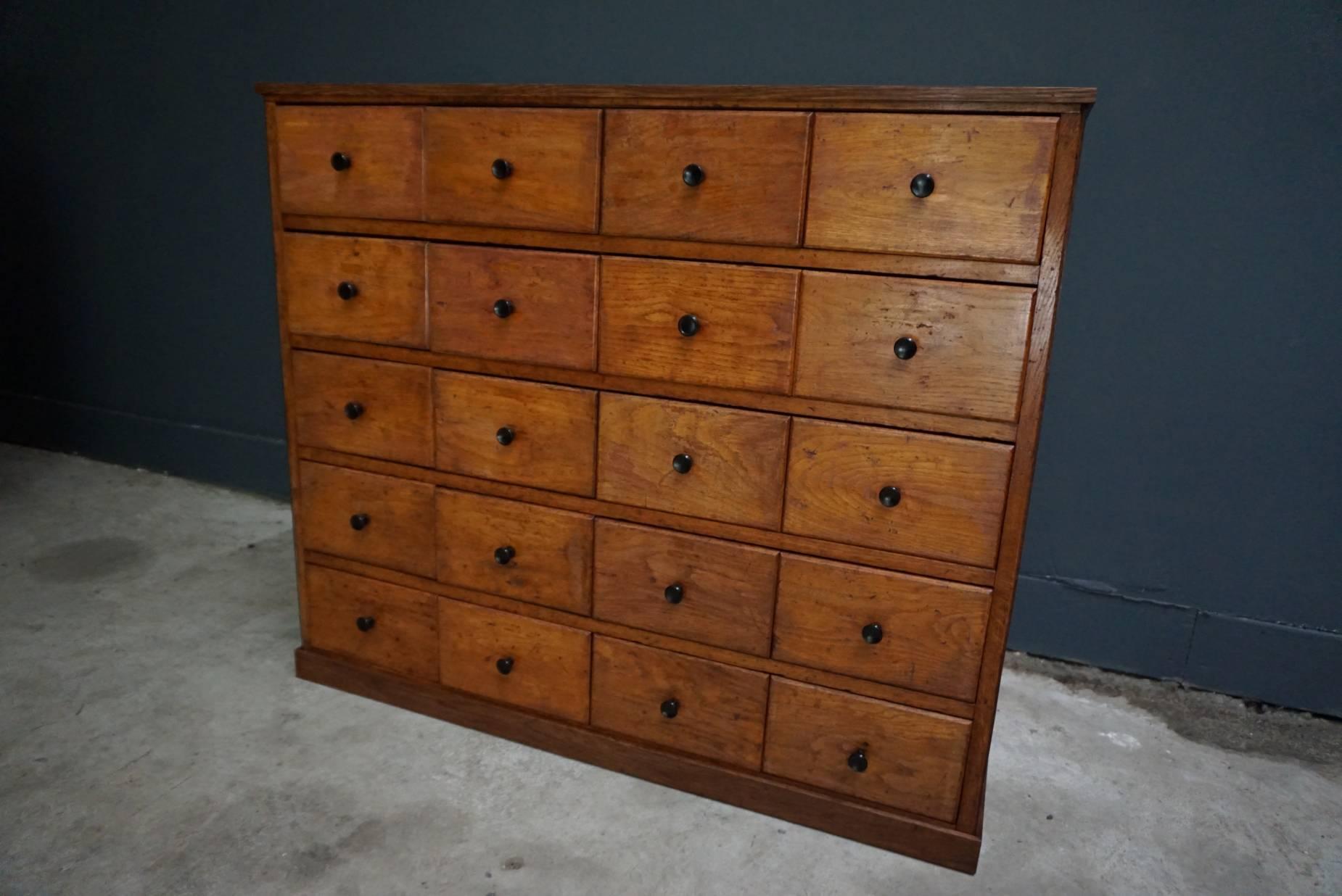 This oak apothecary cabinet was designed and made circa 1930 in the Netherlands. It features 20 drawers and it remains in a very good vintage restored condition. The inside of the drawers measure: 45 x 21.5 x 13 cm.