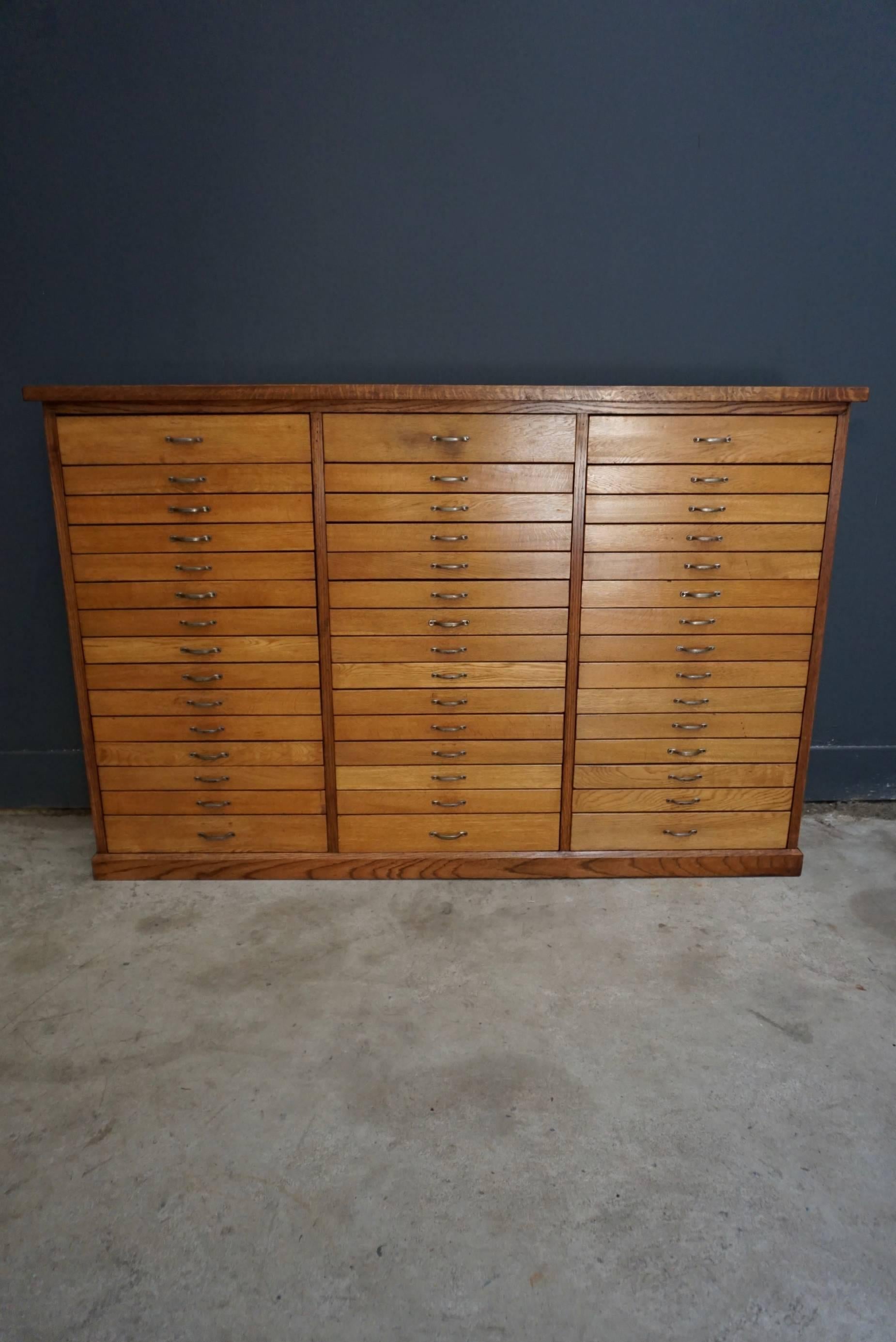 This oak apothecary cabinet was designed and made, circa 1950 in the Netherlands. It features 45 drawers with metal hardware. The inside of the top drawers measure: 27 x 45 x 7.5 cm and the bottom drawers: 27 x 45 x 4 cm.