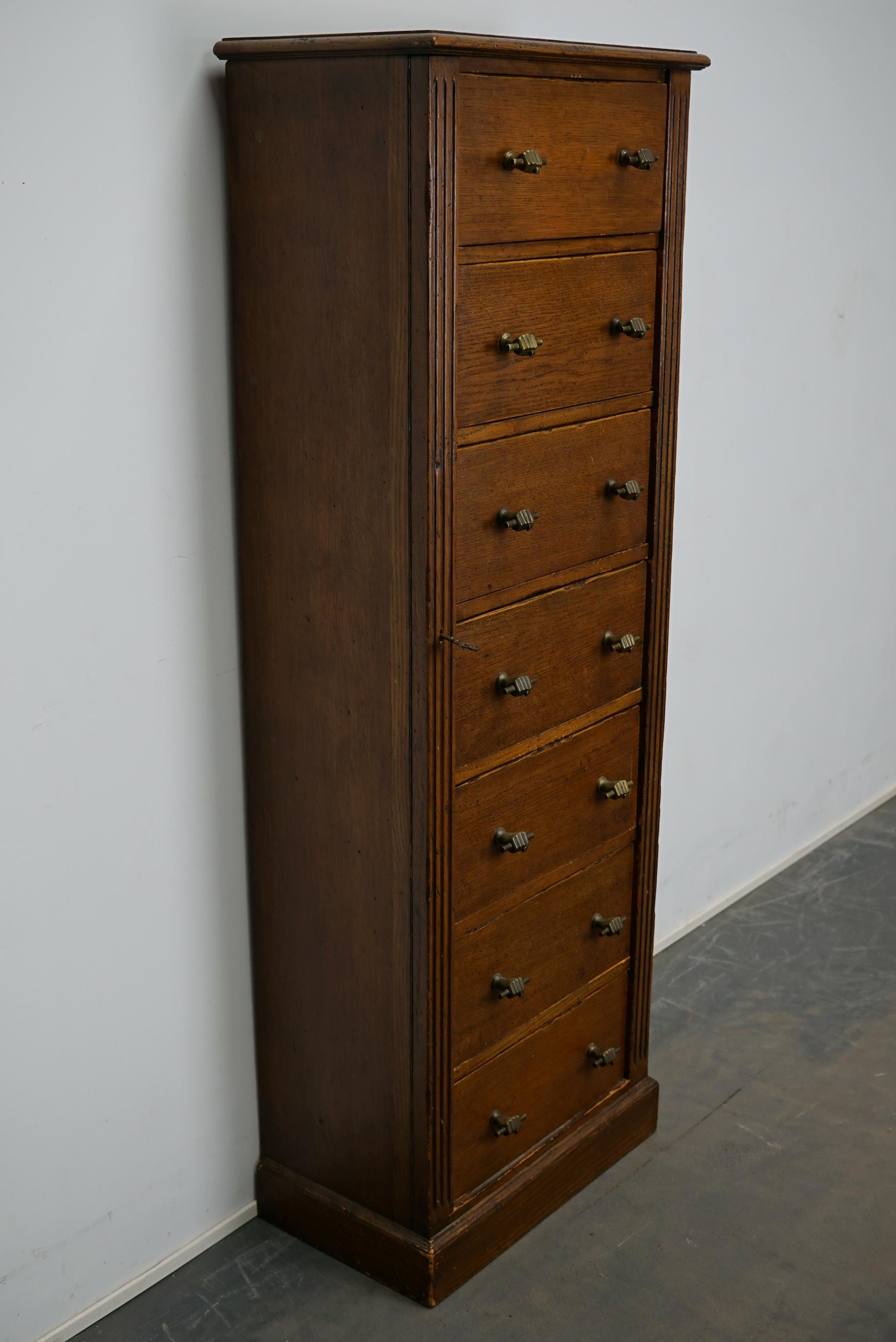 This apothecary cabinet with large drawers was made circa 1950s in the Netherlands. It features 7 drawers in oak veneer with very special hand shaped handles. It remains in a good restored condition. The drawers are lockable with the original key.