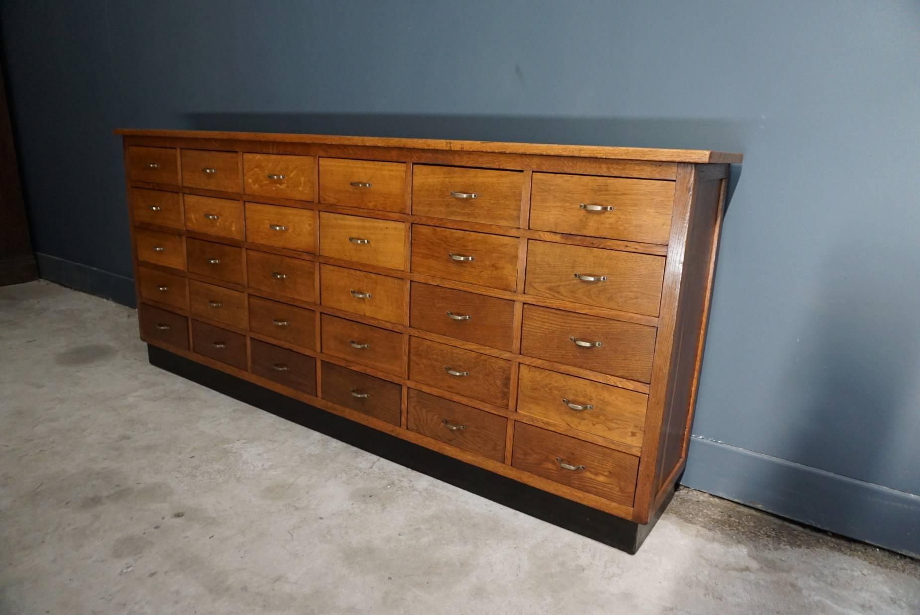 This oak apothecary cabinet was designed and made, circa 1950 in the Netherlands. It features 30 drawers with metal hardware. The inside of the drawers measure: 28 x 28.5 x 11 cm.