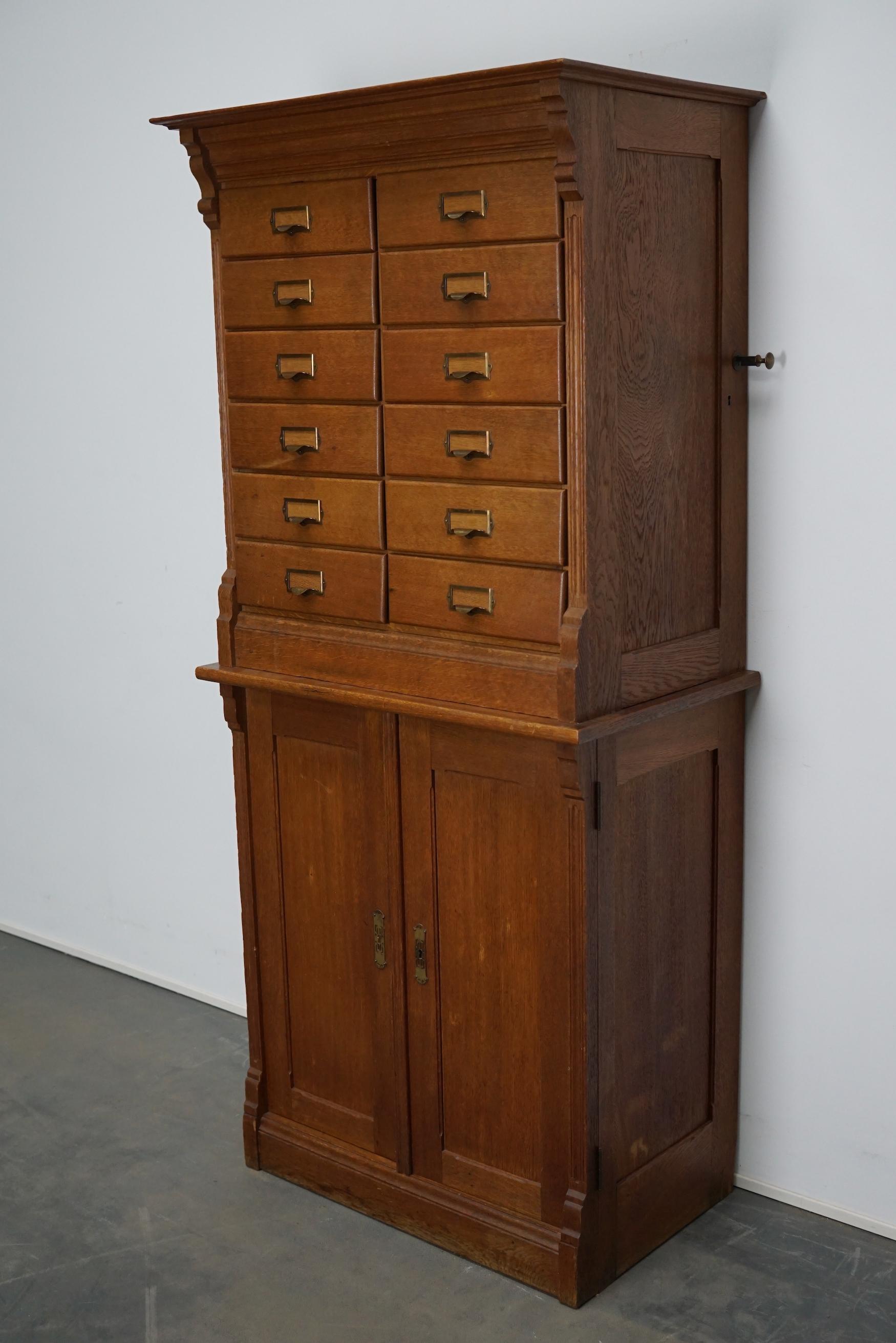 This apothecary cabinet was made circa 1930s in The Netherlands. It features 12 drawers with nice brass handles and two doors with shelves behind it. The drawers can be locked with a central locking mechanism, most of the drawers lock but the