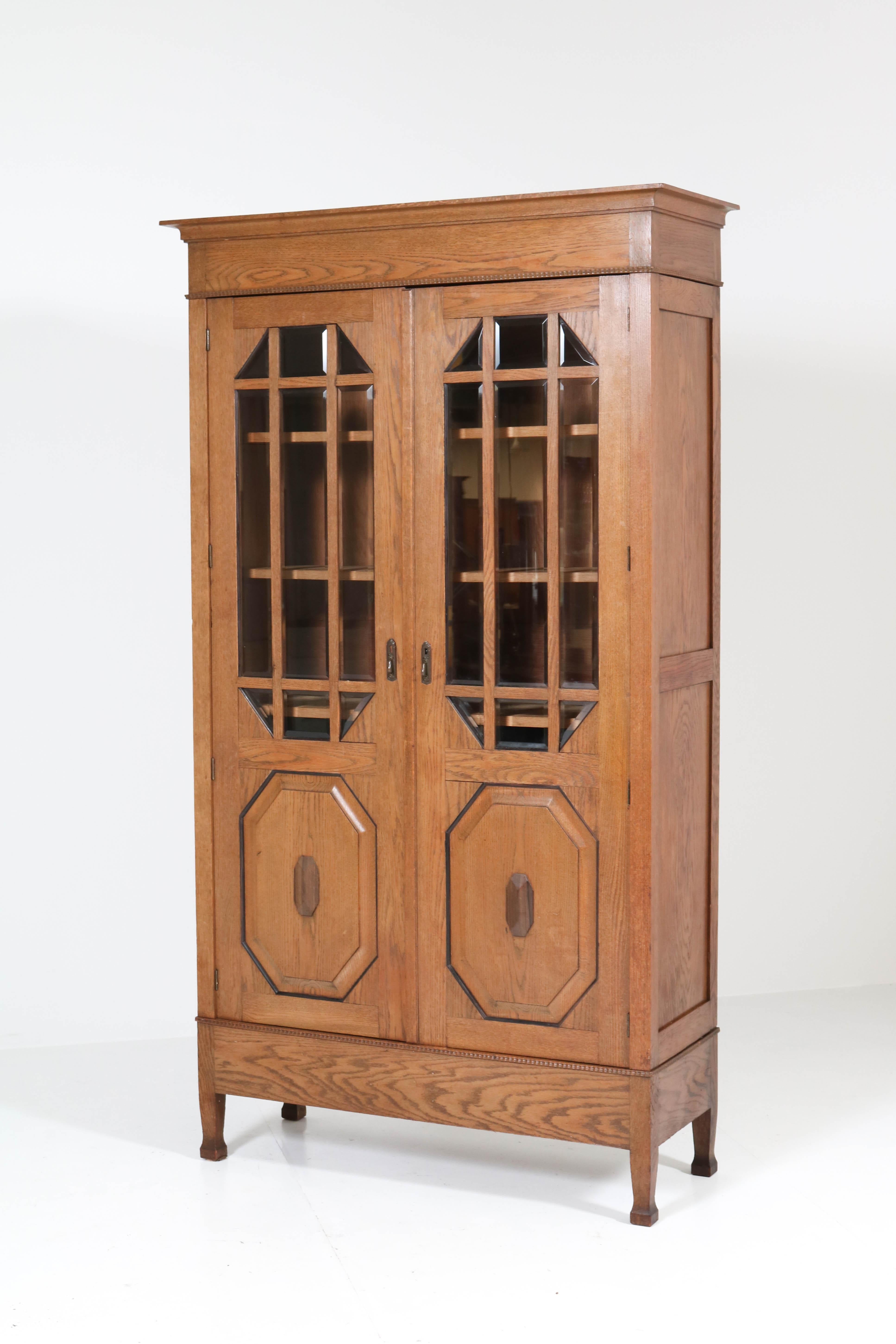 Wonderful and rare Art Nouveau Arts & Crafts bookcase.
Striking Dutch design from the 1900s.
Solid oak with ebony Macassar lining and decoration.
The doors have eighteen original beveled glass pieces.
Four original solid oak shelves, adjustable