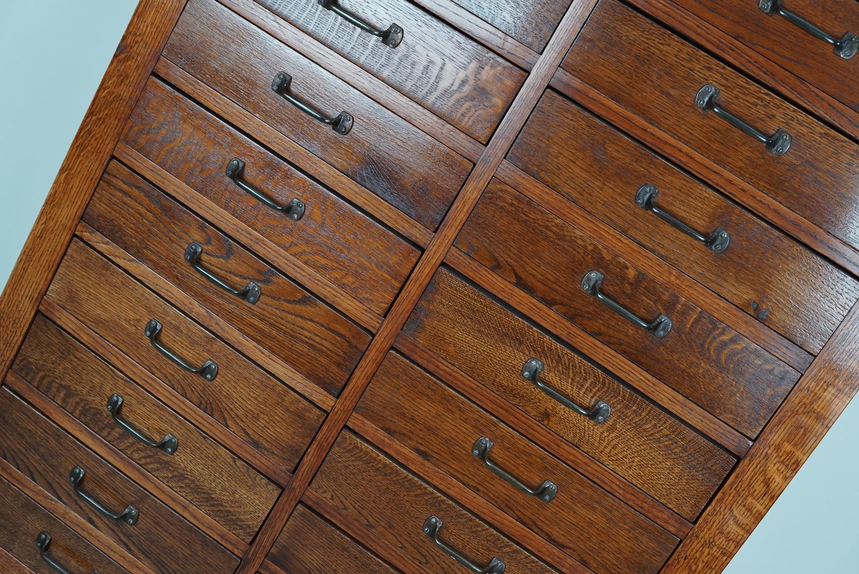 This apothecary cabinet was made circa 1930s in The Netherlands. It features 20 drawers with nice original metal handles. It is made from oak and beech and it remains in a very good antique condition. The interior dimensions of the drawers are: D 34