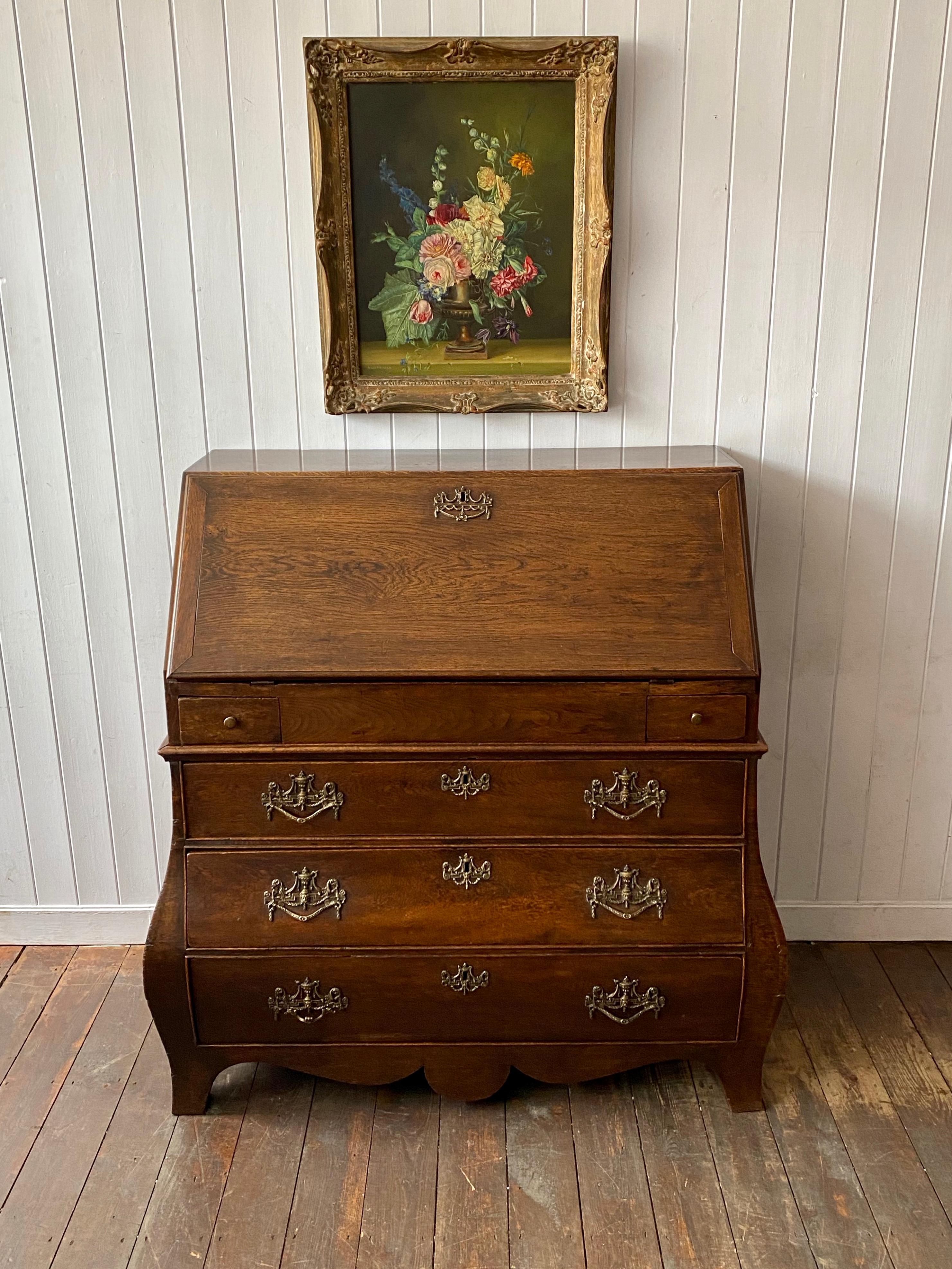 A Dutch oak Bombe Bureau Secretaire, circa 1800. Having a lovely organic shape and color. The fall front opens to reveal a nicely fitted interior with pigeon holes, drawers, secret slide and secret release drawer to its floor. The lower section