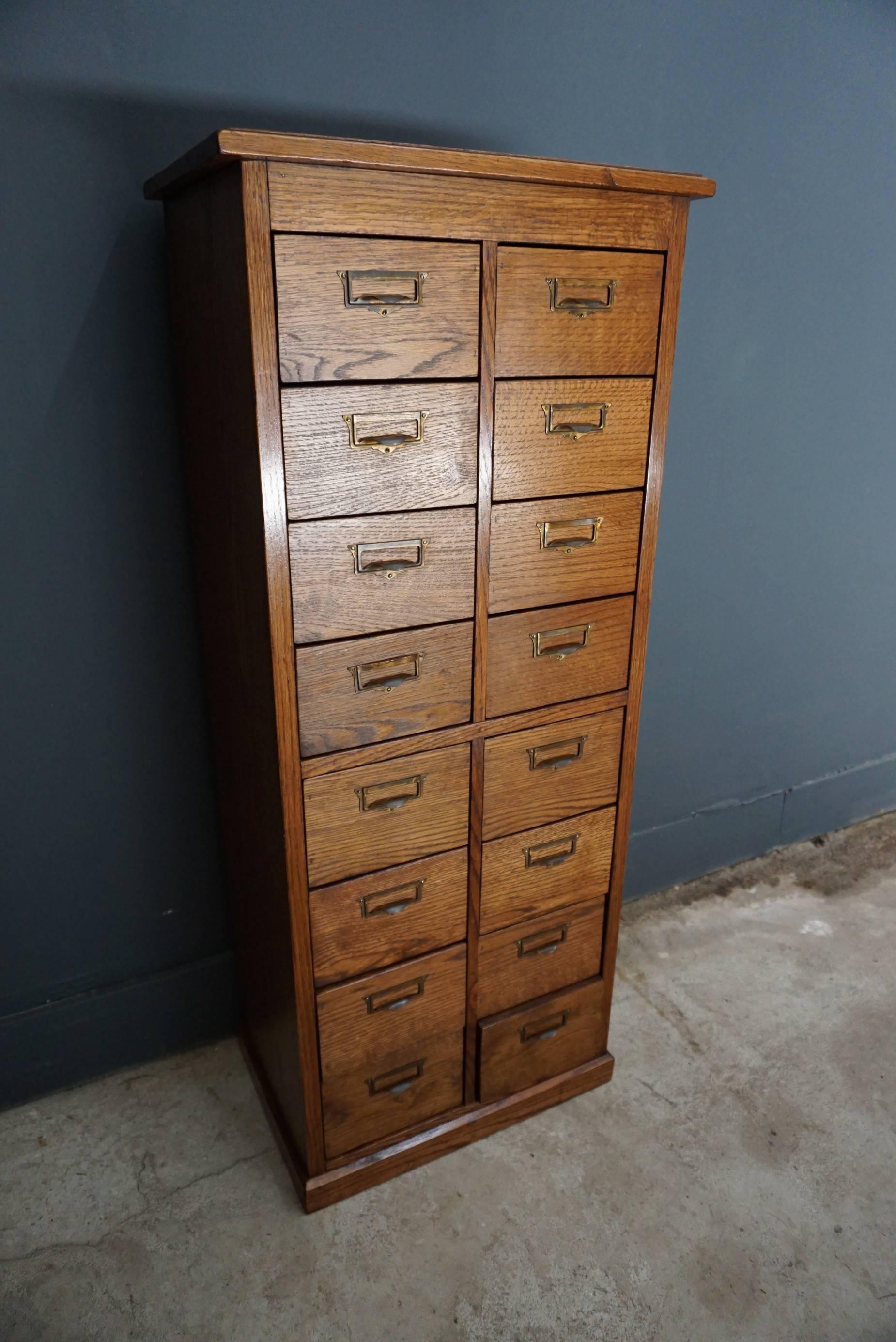 This oak apothecary cabinet was designed and made, circa 1930 in The Netherlands. It features 16 drawers with brass hardware. The inside of the drawers measure: 26.5 x 17.5 x 10.8 cm.