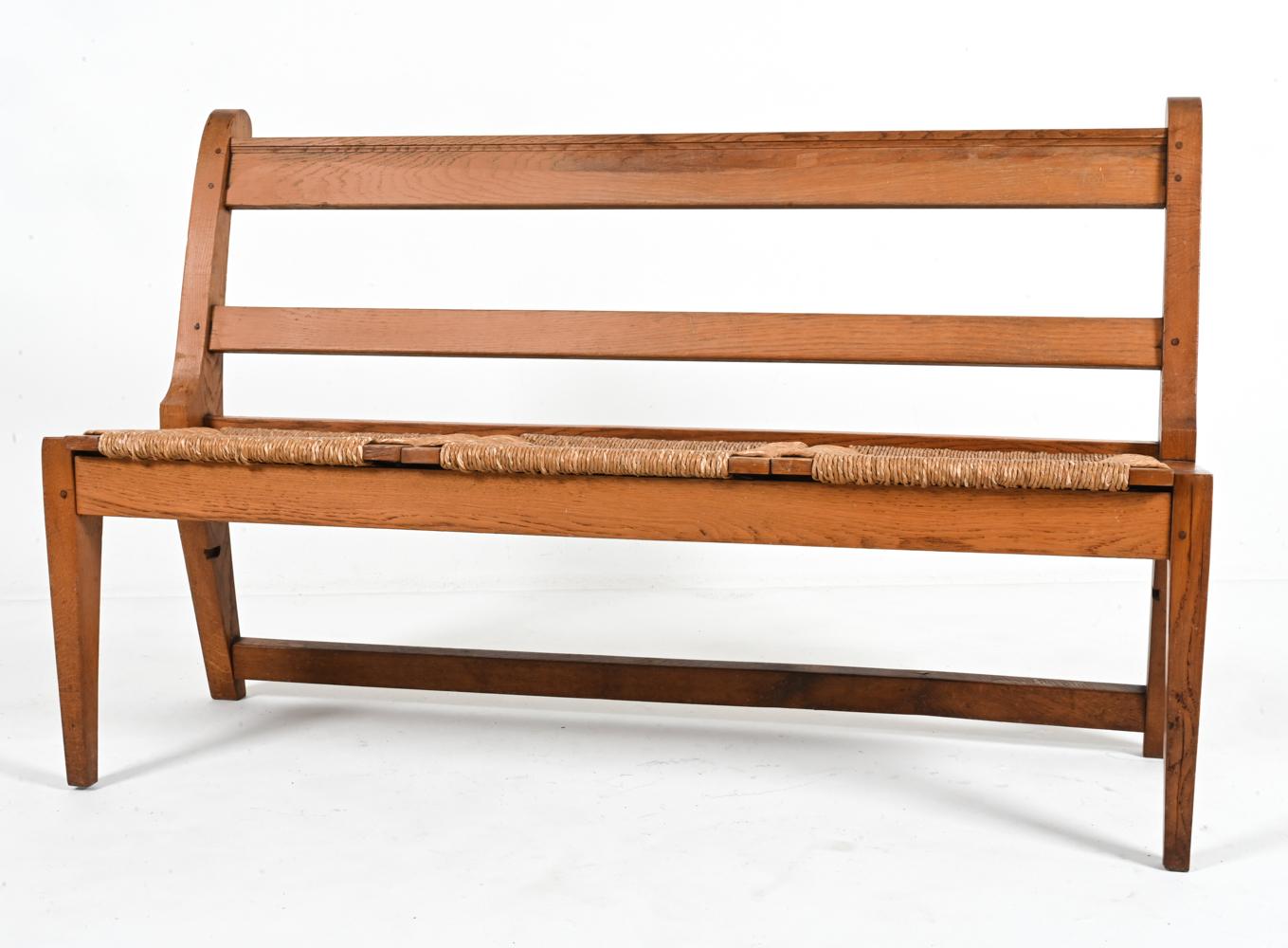 Steeped in history, this captivating oak and rush bench, crafted during the 1930's, embodies the enduring design of a classic church pew. 

The solid oak frame, boasting rich warmth and superior durability, promises stability for years to come. The