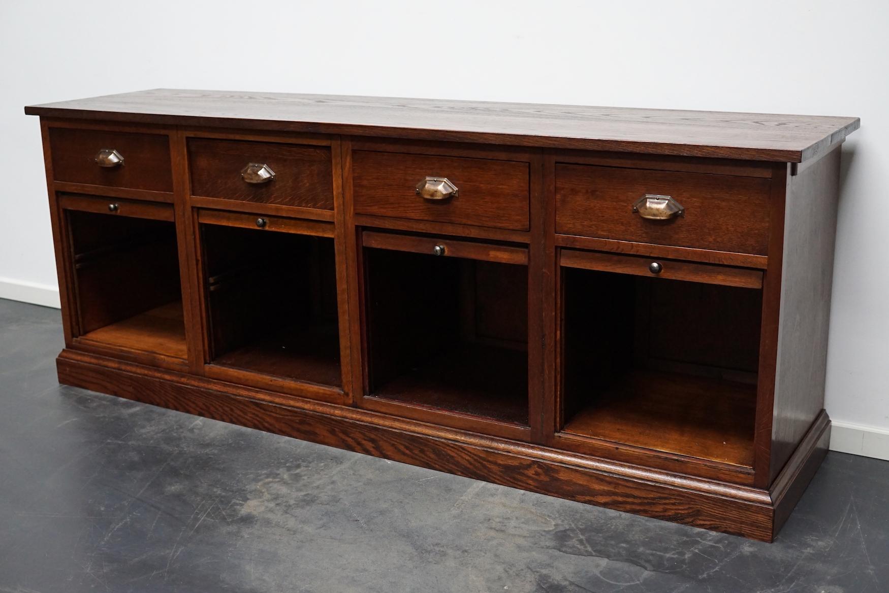 This very unusual sideboard was made from oak in the Netherlands ca 1930's. It features 4 compartments with sliding doors and 4 drawers with brass cup handles. It is in a very good restored condition.