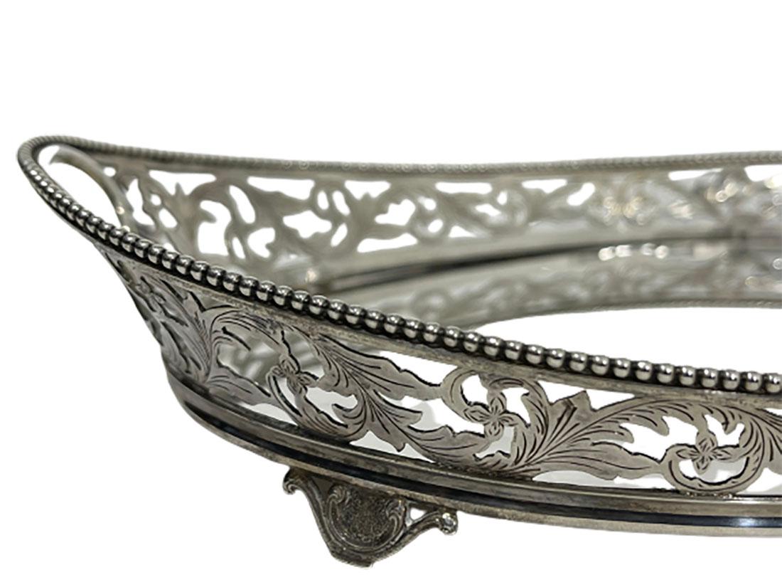 Dutch oval silver tray by W. Brehm, 1920. 

An oval silver tray with raised edge, decorated and openwork with leaf motif and on the edge with pearl rim. 2 oval integrated handles. The tray raised at 4 feet. The silversmith is Wilhelmus Brehm,