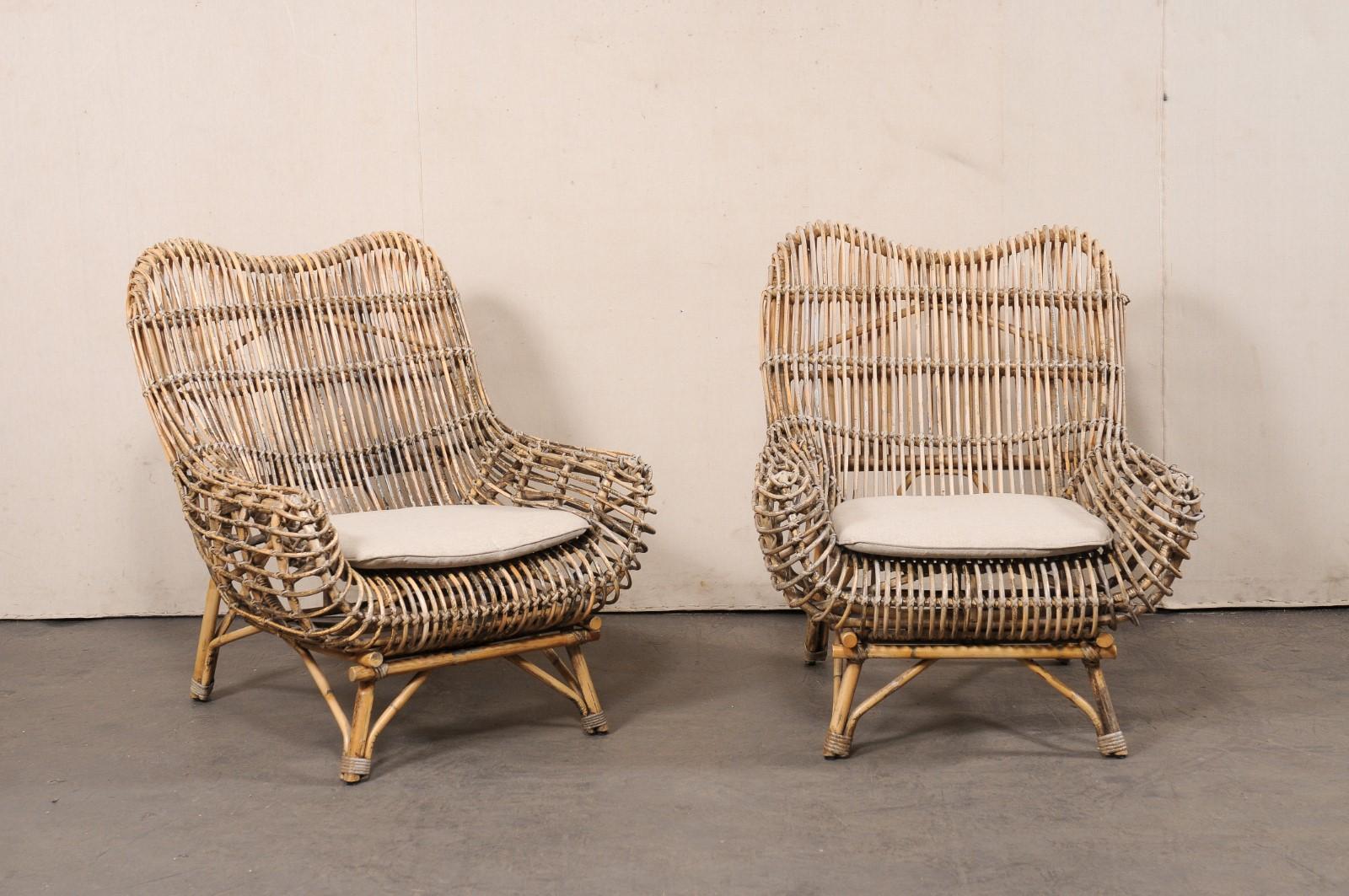 A pair of Dutch bamboo reed and rattan occasional chairs. These vintage chairs from the Netherlands have been created with soft, curvy lines out of bent and molded bamboo reeds and rattan. The upper top rail has a gently swag that slopes downward