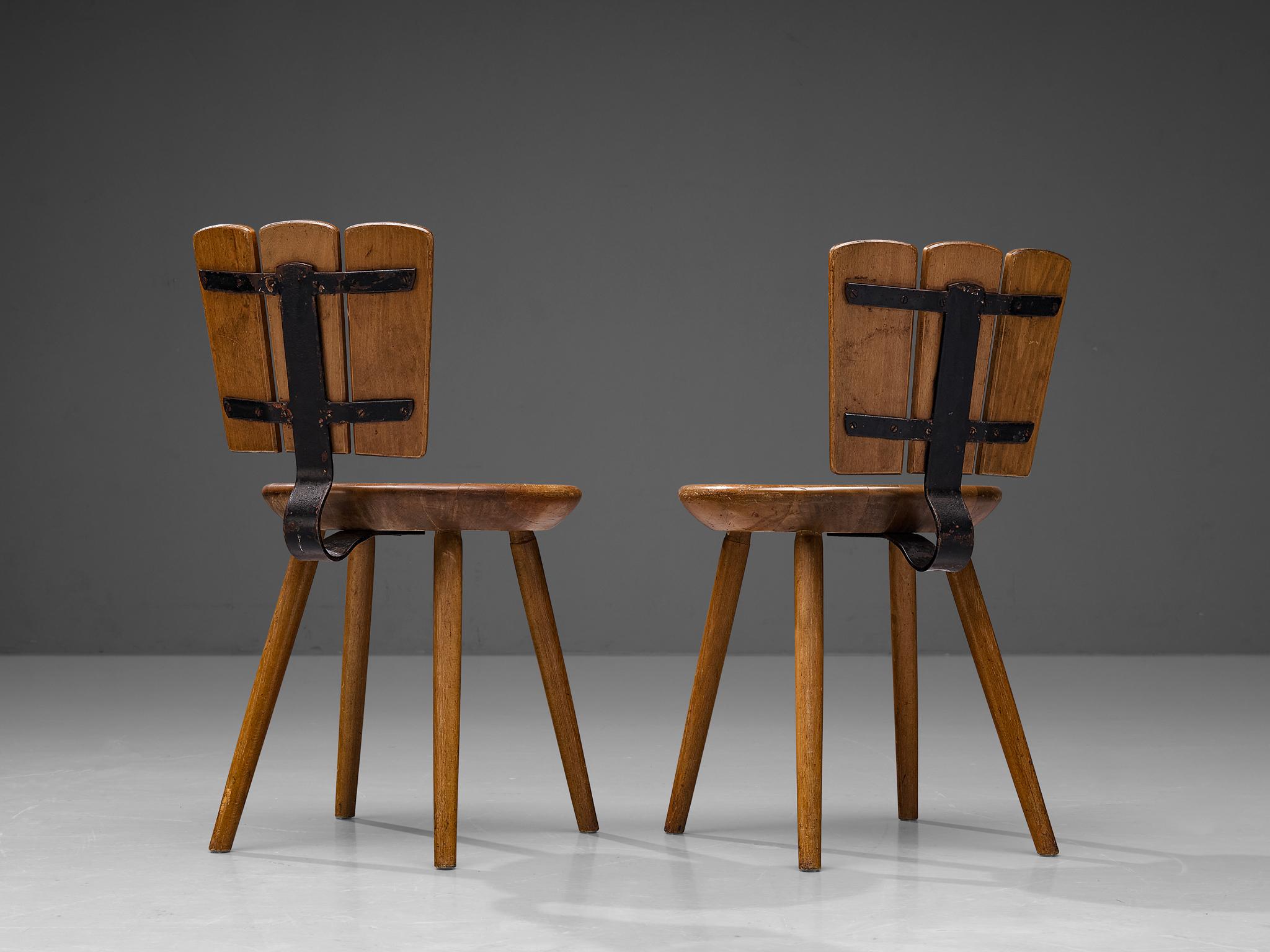 Pair of dining chairs, stained beech, cast iron, The Netherlands, 1970s. 

Rustic pair of Dutch dining chairs made in the 1970s. This design in stained beech features a curved cast iron backrest support. Despite the sturdy look of the design, these