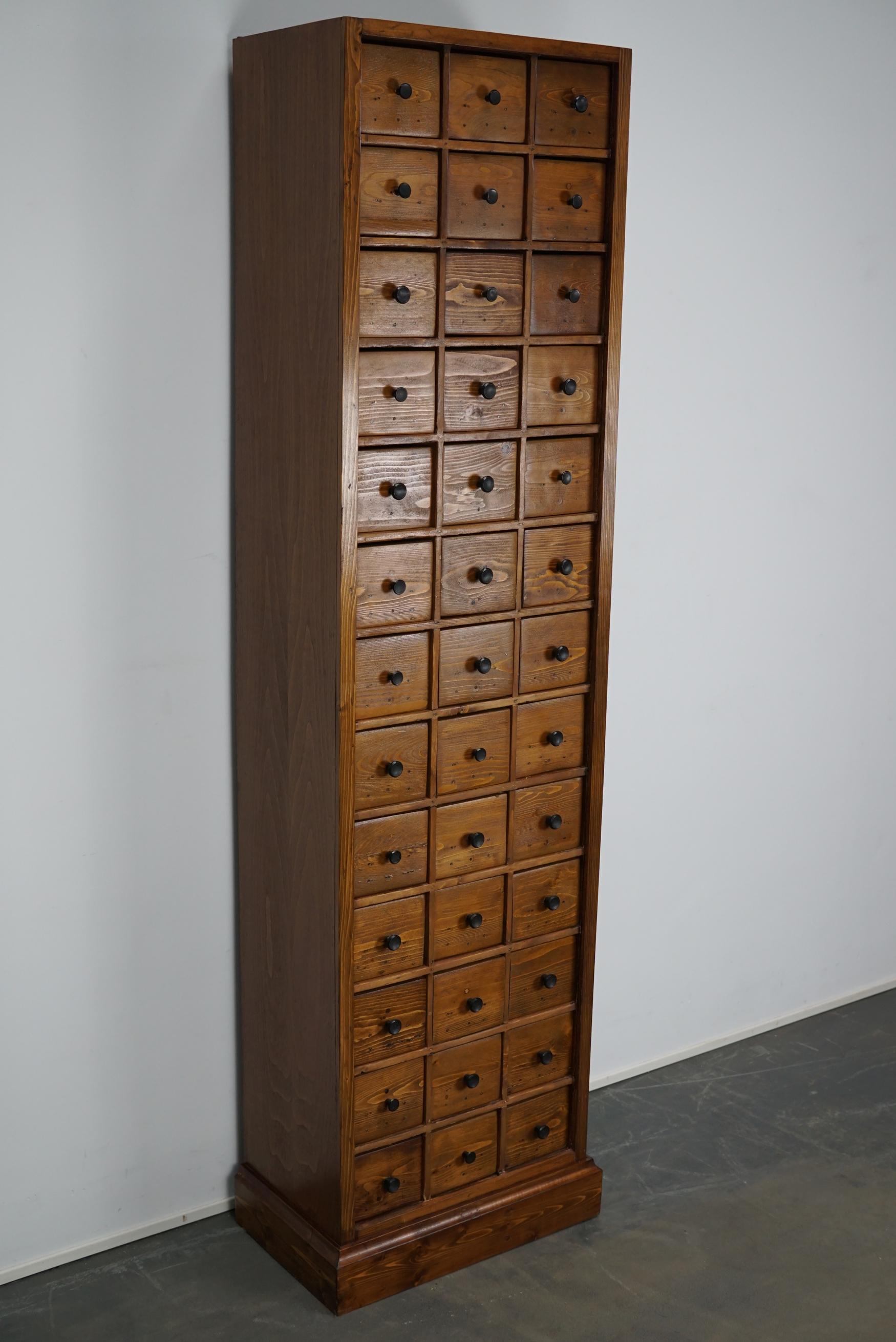 This apothecary cabinet of drawers was designed, circa 1950s in the Netherlands. The piece is made from pine and features 39 drawers with black hardware. The interior dimensions of the drawers are: D 25 x W 11.5 x H 11 cm.