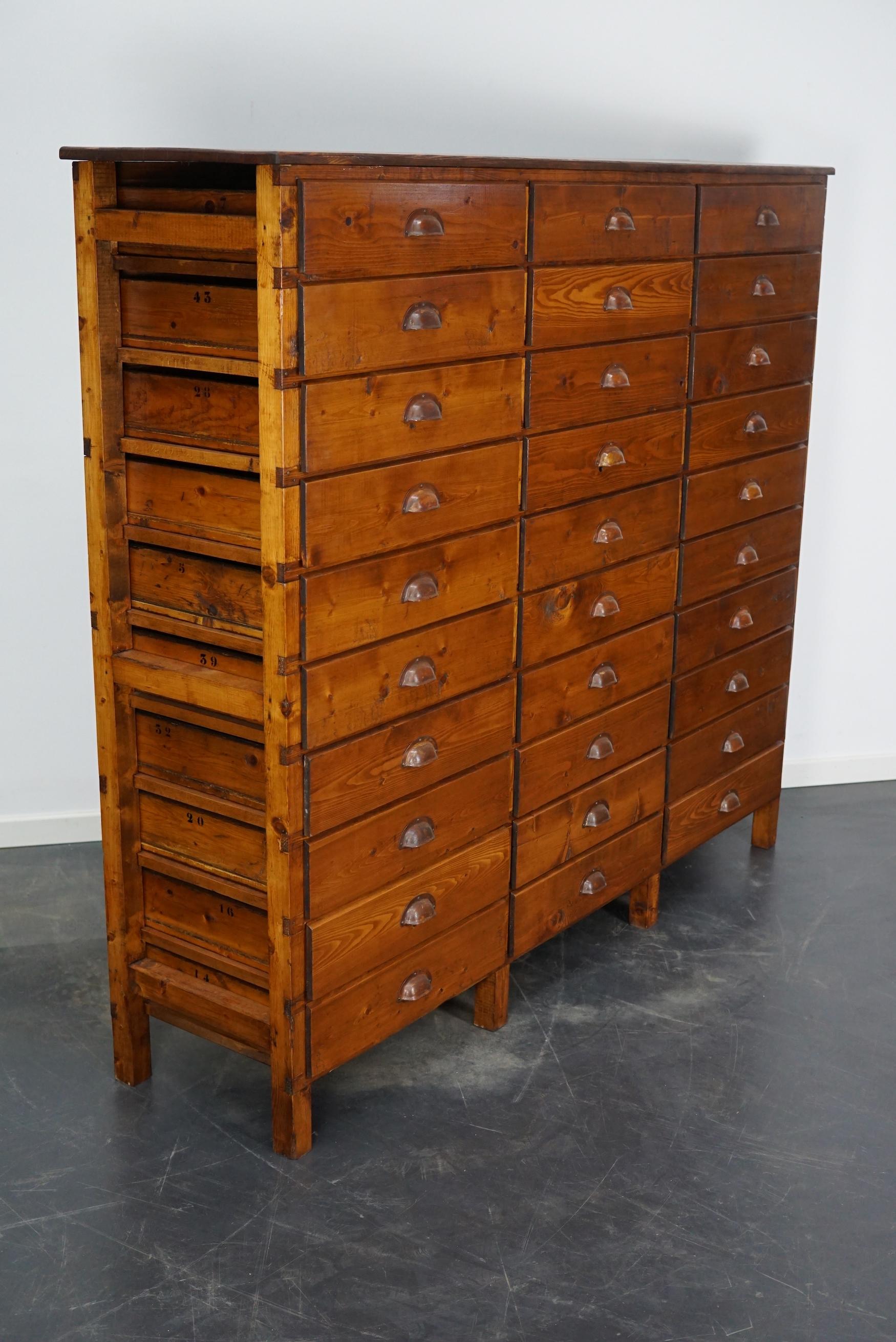 This apothecary cabinet was designed and made from pine circa 1950 in the Netherlands. It features 30 decent sized drawers with metal hardware. The inside of the drawers measure: DWH 38 x 47 x 8.5 cm.